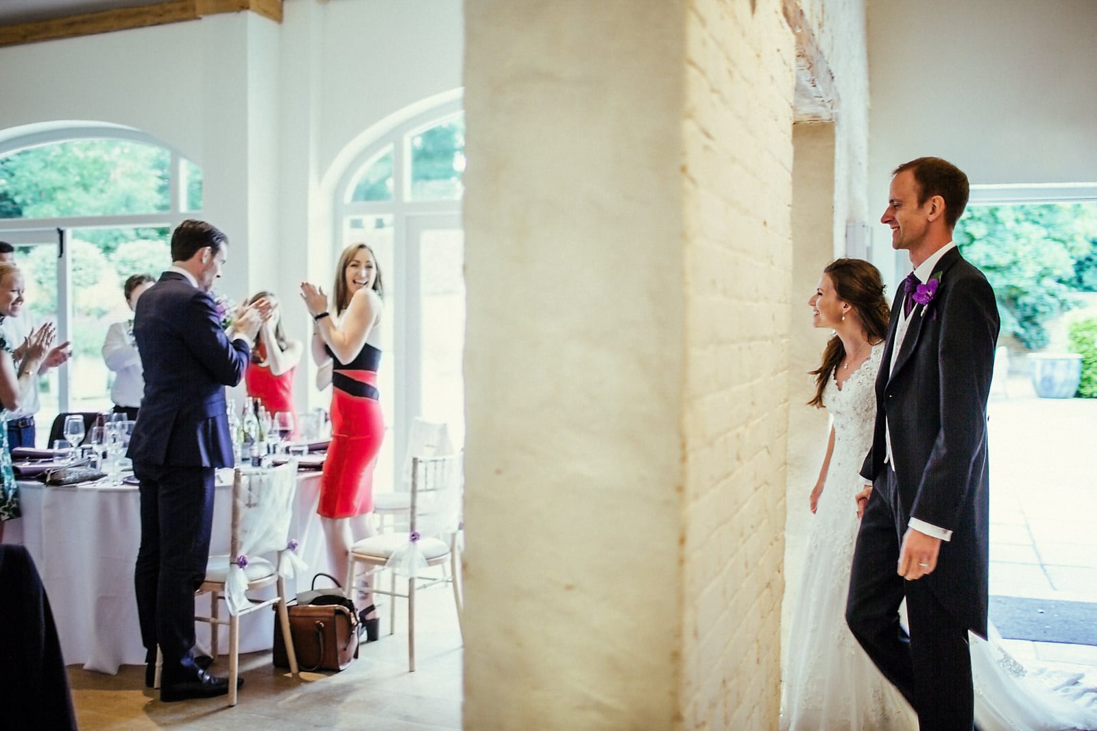 Bride and groom walking into their wedding reception with their guests cheering at Dorney Court