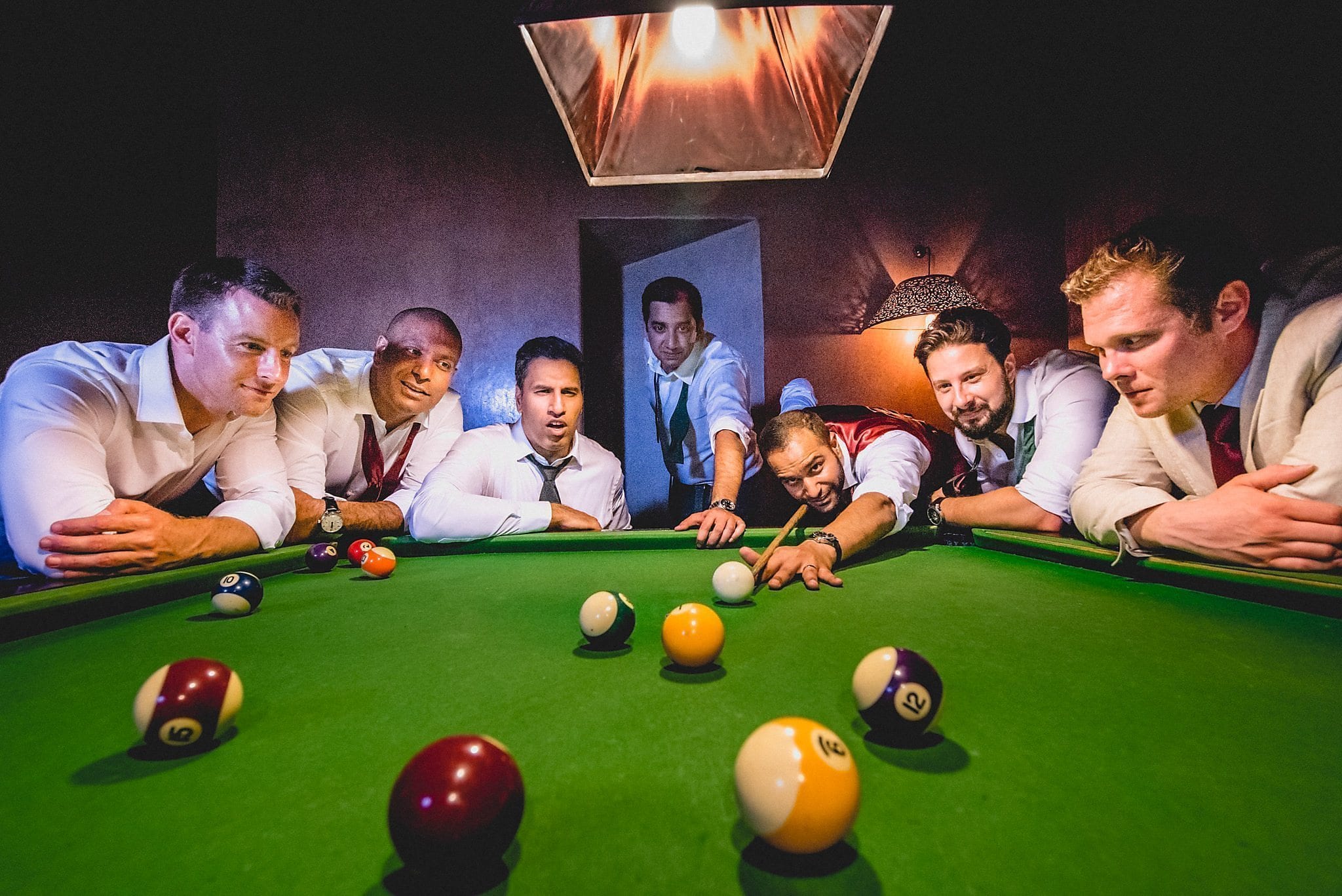 Groom and groomsmen play pool at their destination wedding at Morocco's Ksar Char Bagh