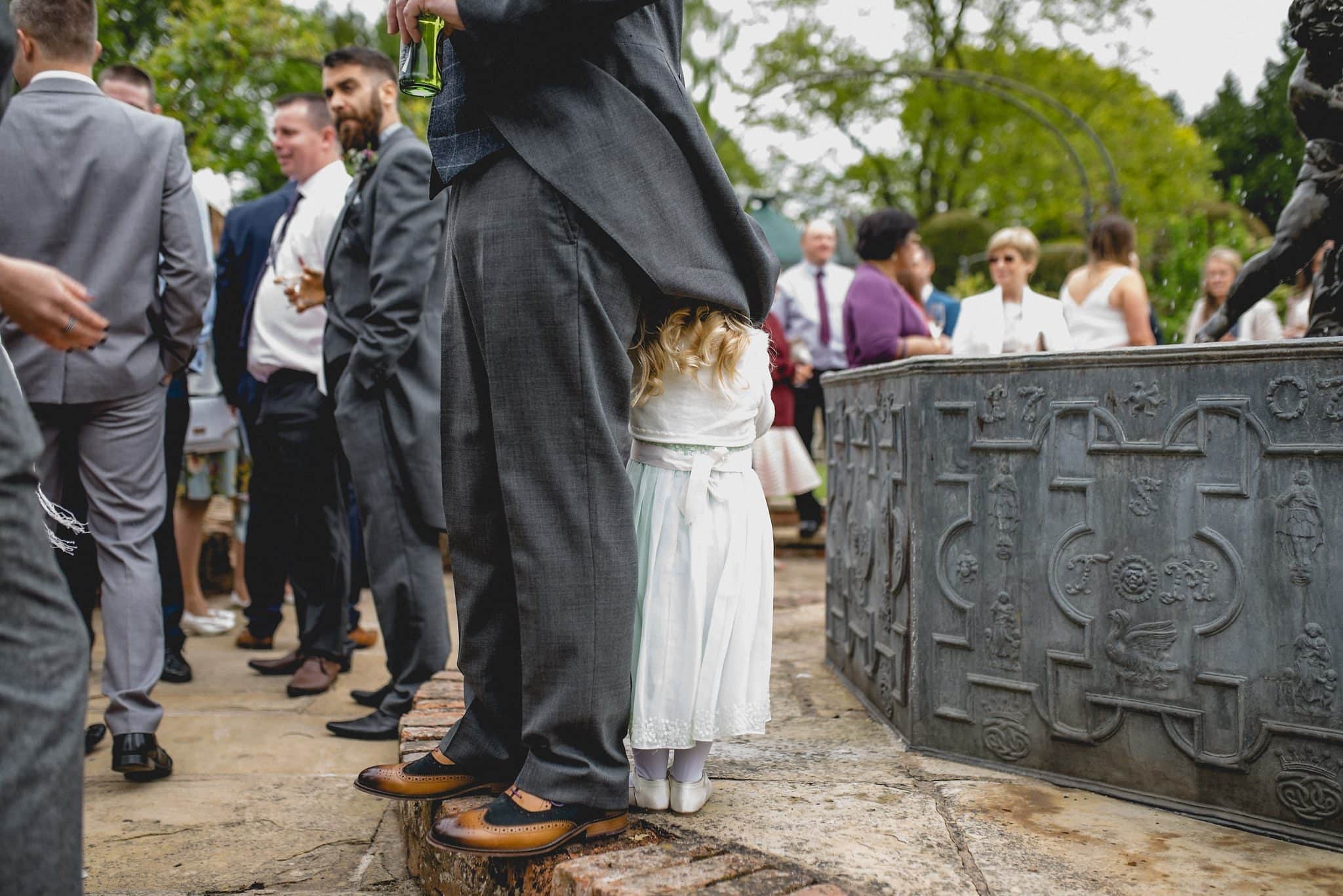 Groom's daughter hiding under his coat tails at his birtsmorton court wedding