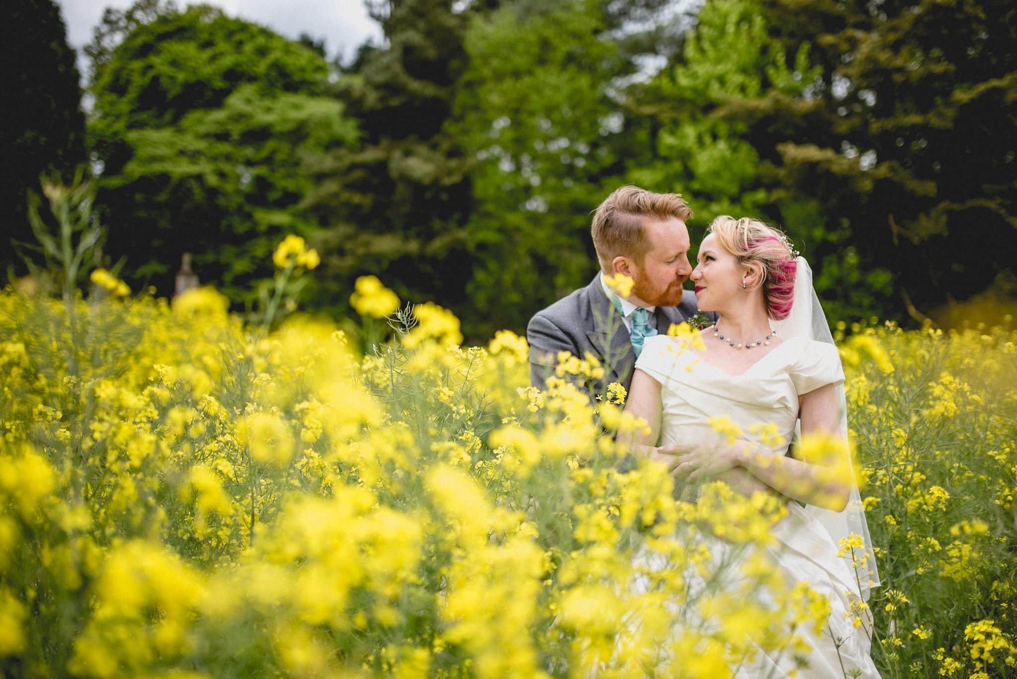 The newlyweds gaze into each others eyes surrounded by bright yellow rapeseed flowers