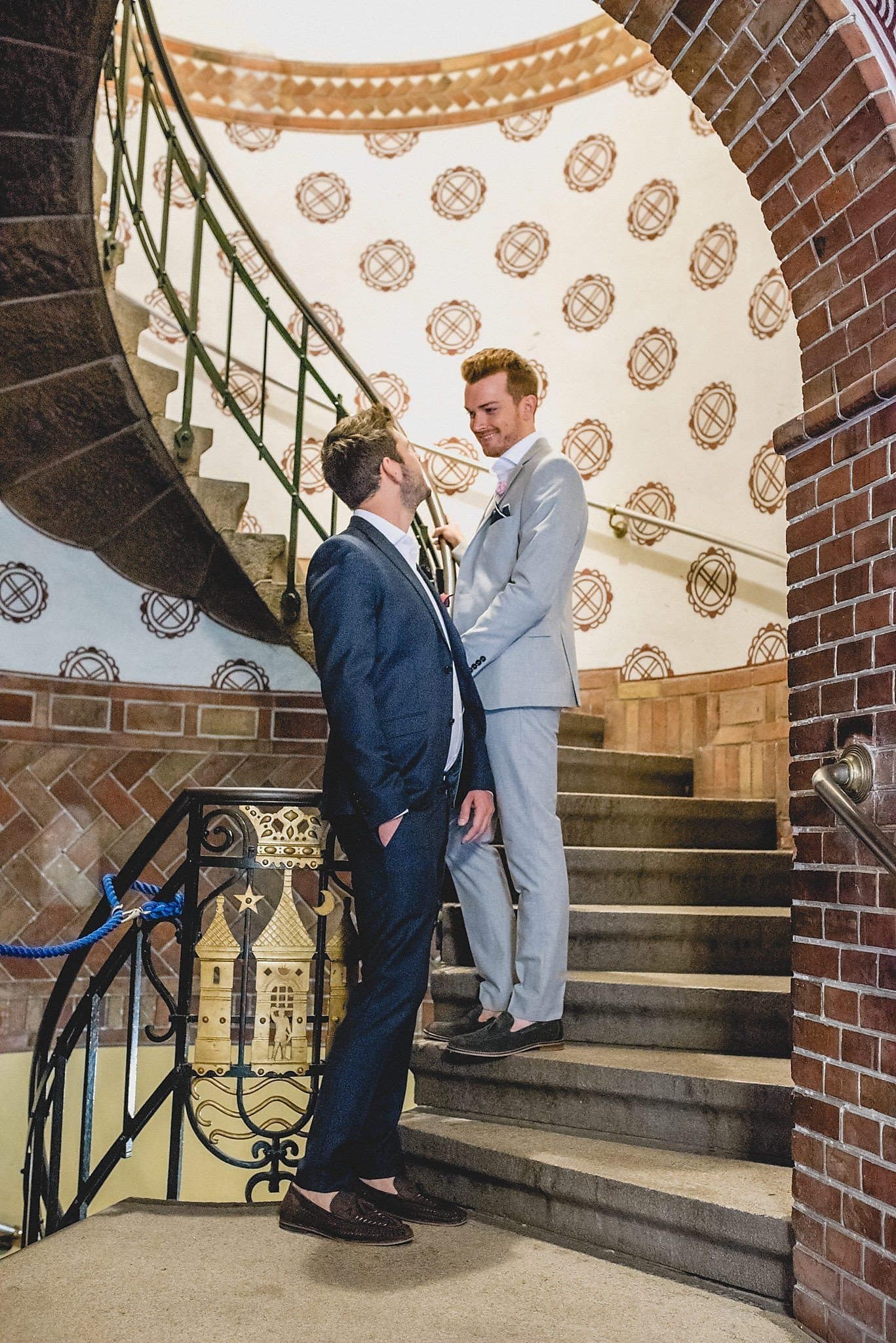 Gay grooms on the spiral staircase of the Copenhagen Radhus before their wedding ceremony