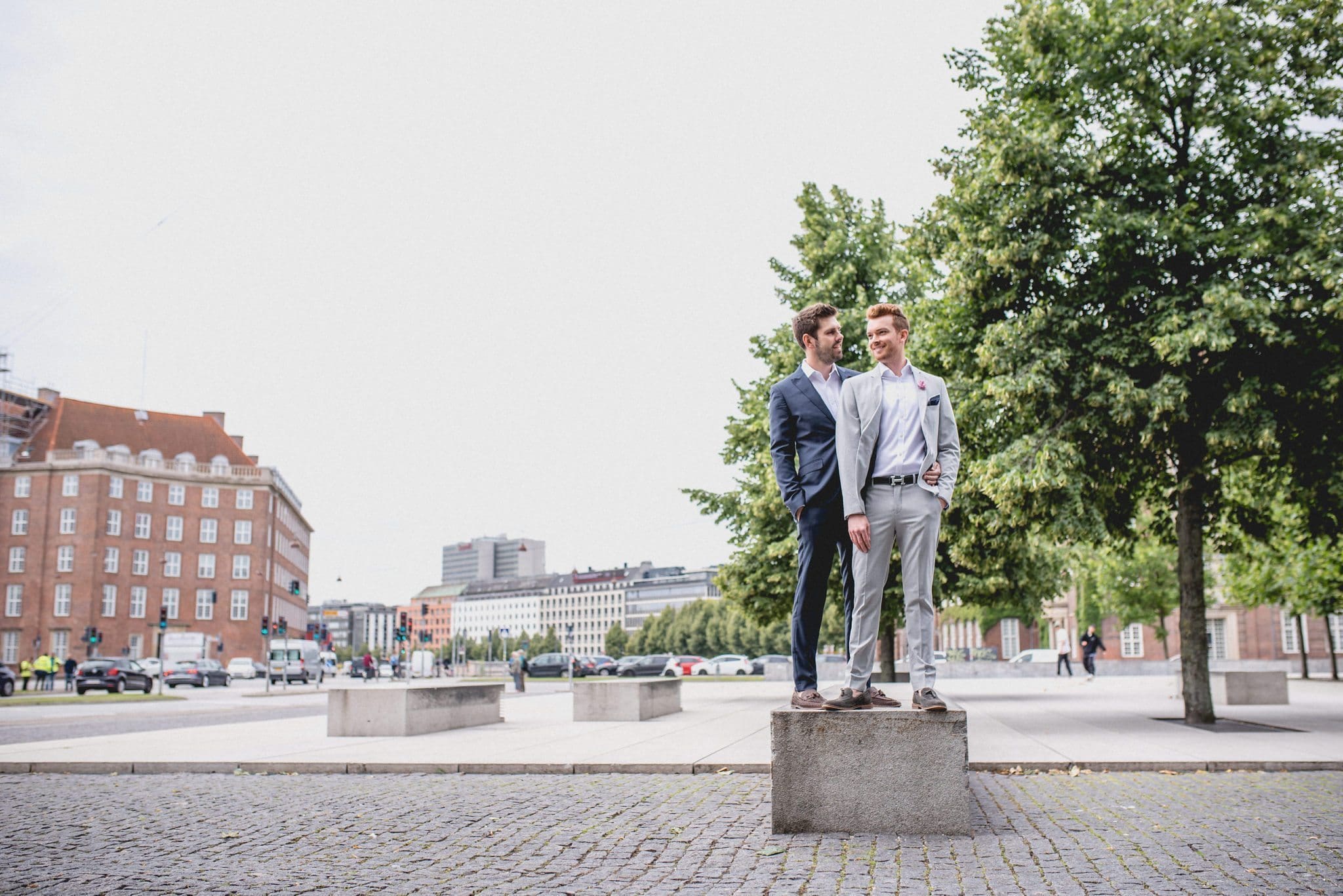 A striking same-sex couple standing together on a pillar in a Copenhagen square