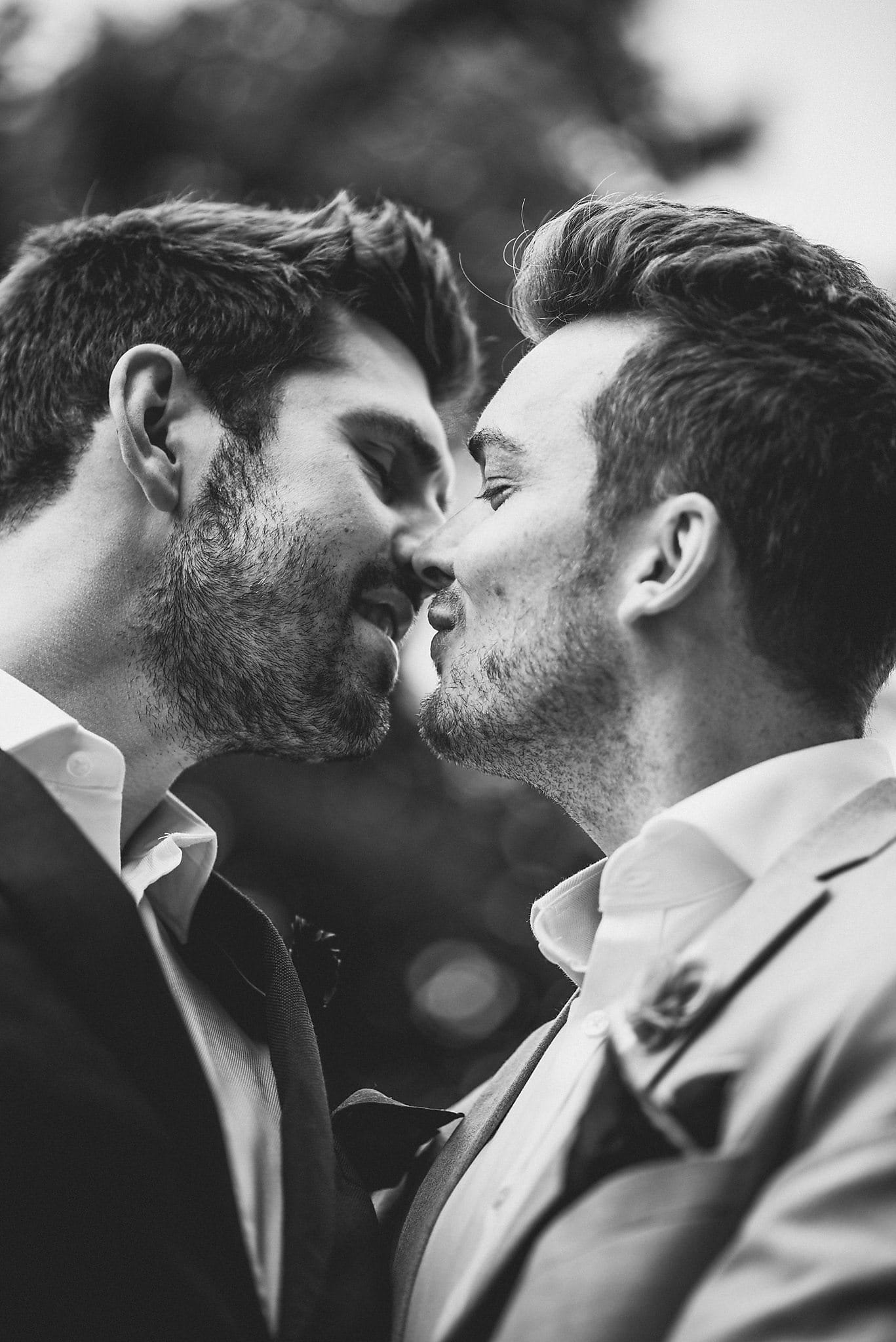 Black and white close-up of two grooms about to kiss in Ørstedsparken, Copenhagen