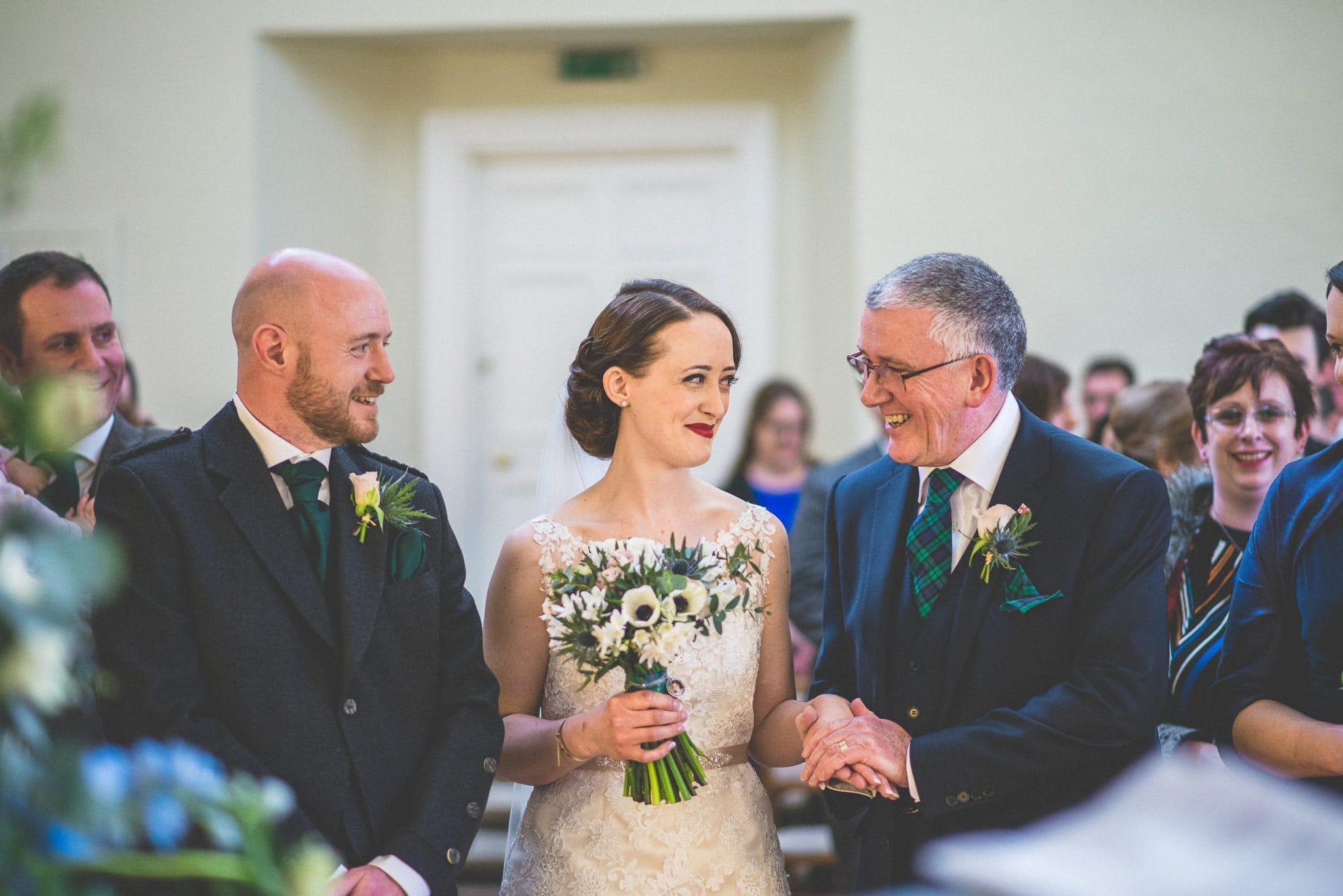 Brides smiles at her father as they reach the end of the aisle in Lantern Hall