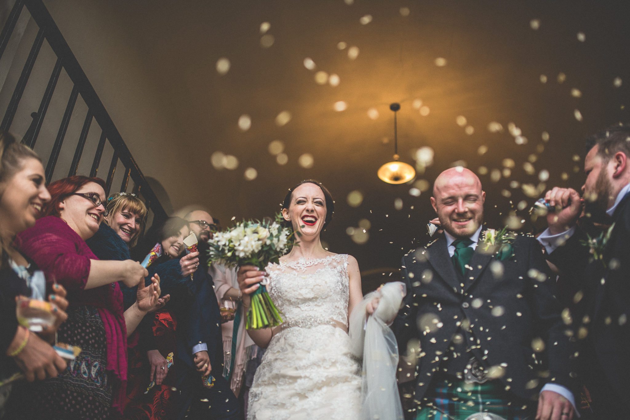 The bride and groom walk down the staircase in a shower of confetti at the Bishops Palace