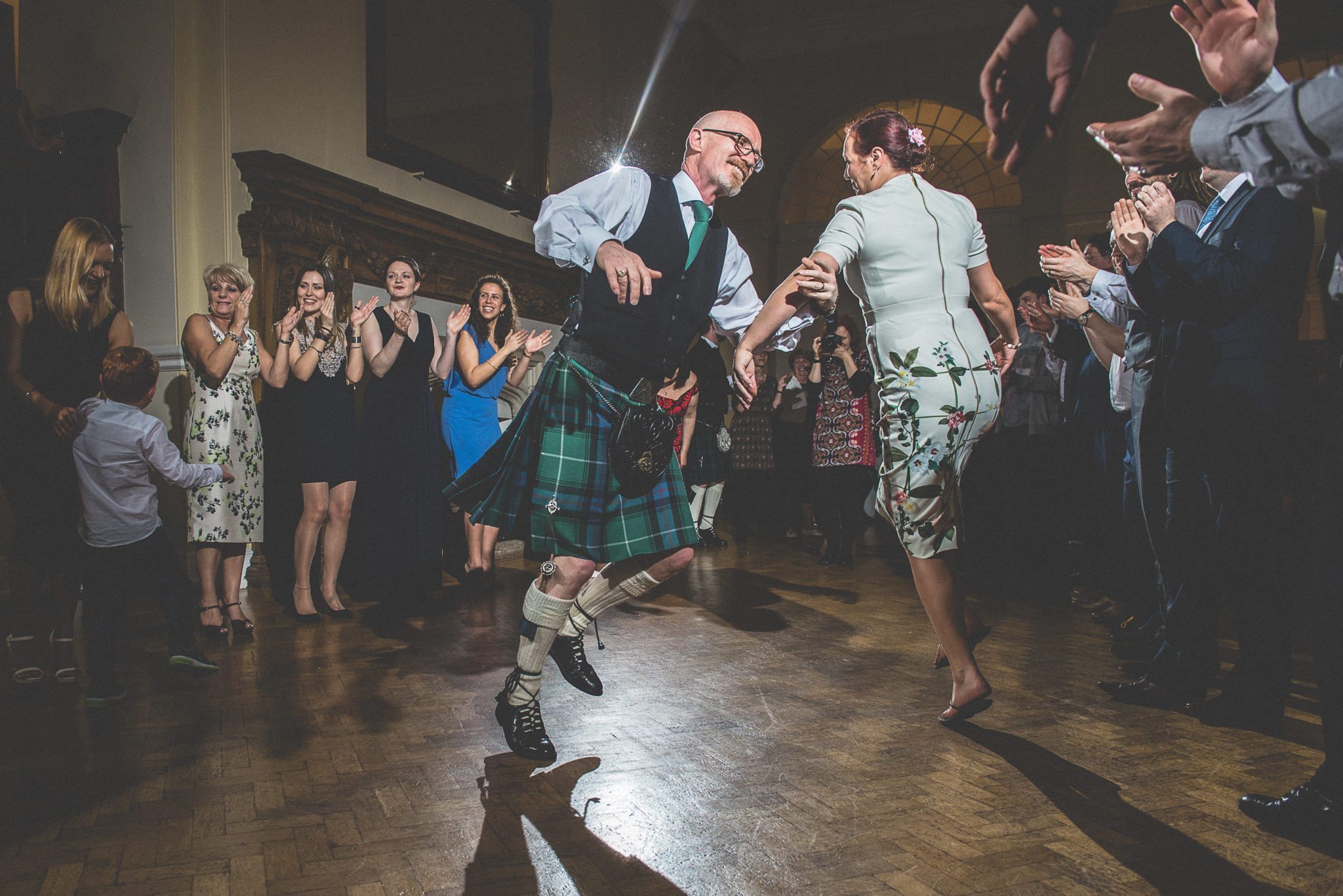 Wedding guests dancing to a Scottish ceilidh in the Great Hall at Farnham Castle