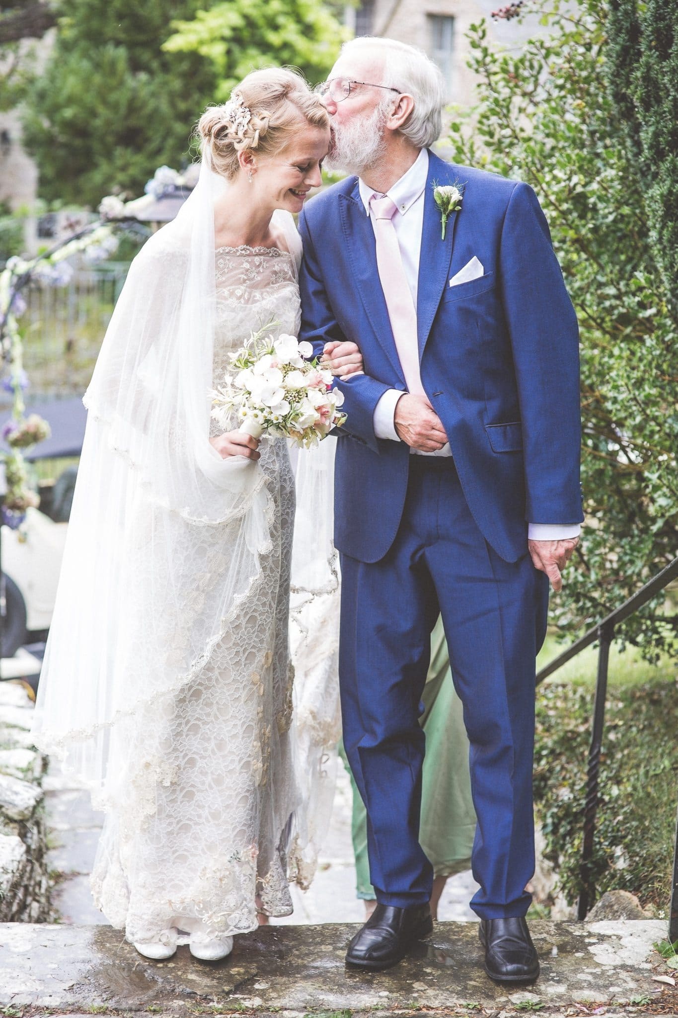 Bride's father kissing his daughter on her forehead at the entrance of the church