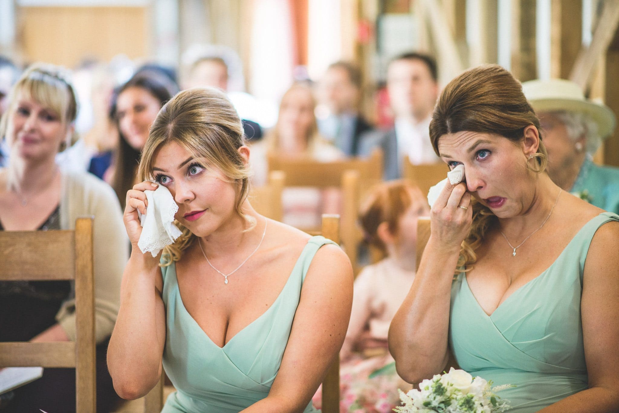 Bridesmaids in mint green dresses wipe tears away during the Gate Street Barn ceremony