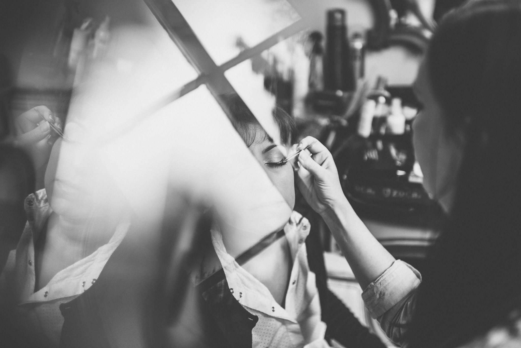 Bride's make up being applied with a window reflection across her face