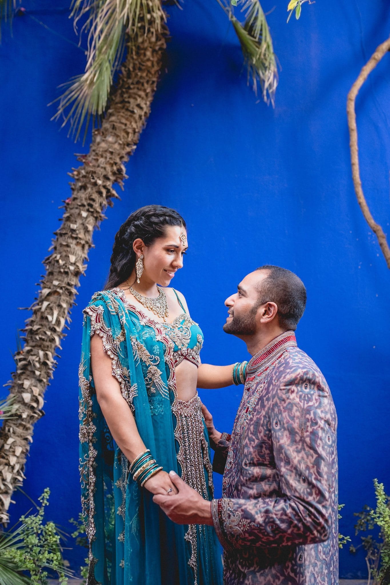 Asian bride and groom stand against the iconic blue walls of the Majorelle Gardens