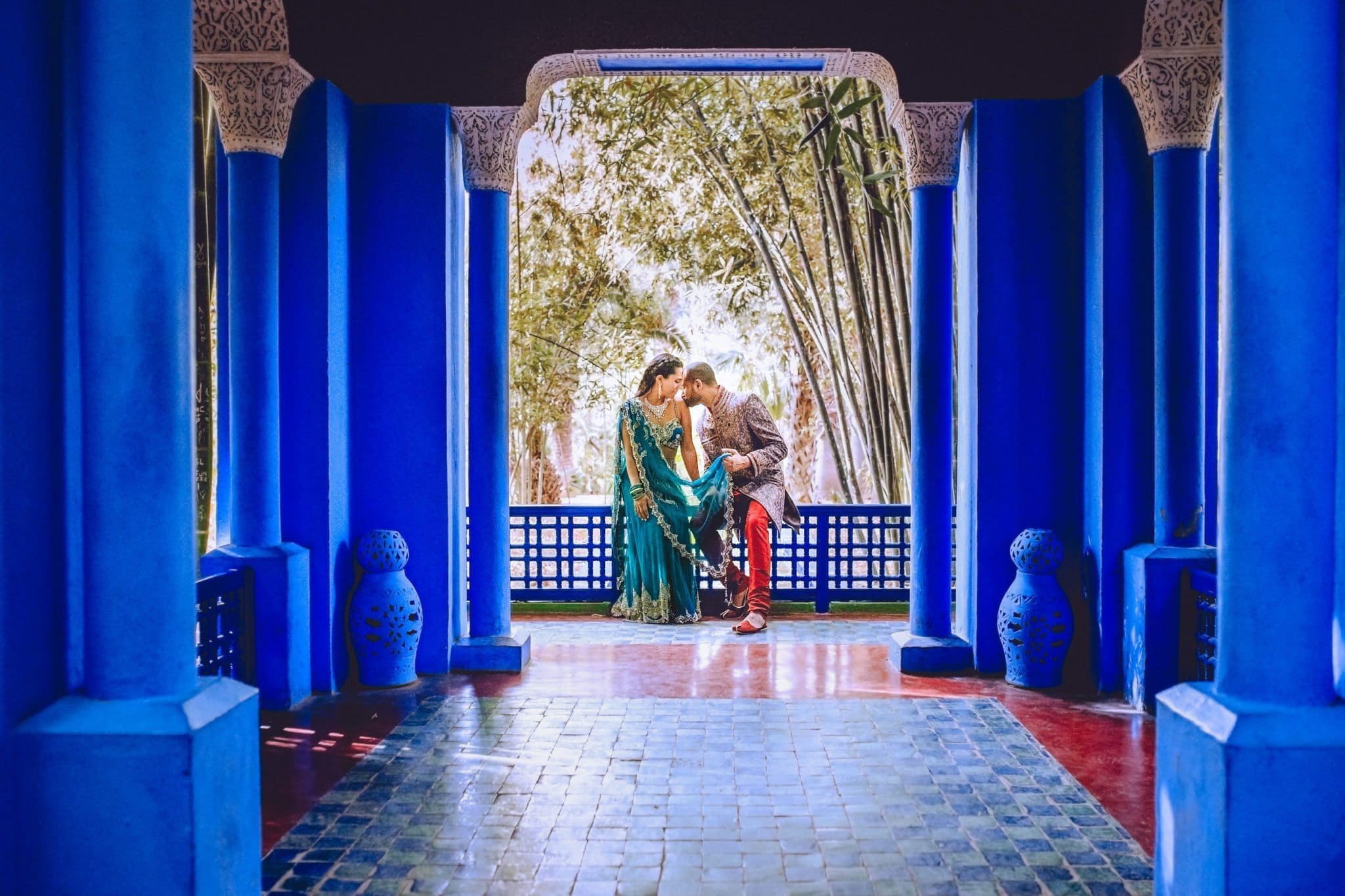 Indian groom kissing his bride's shoulders overlooking the Marrakech Majorelle Gardens