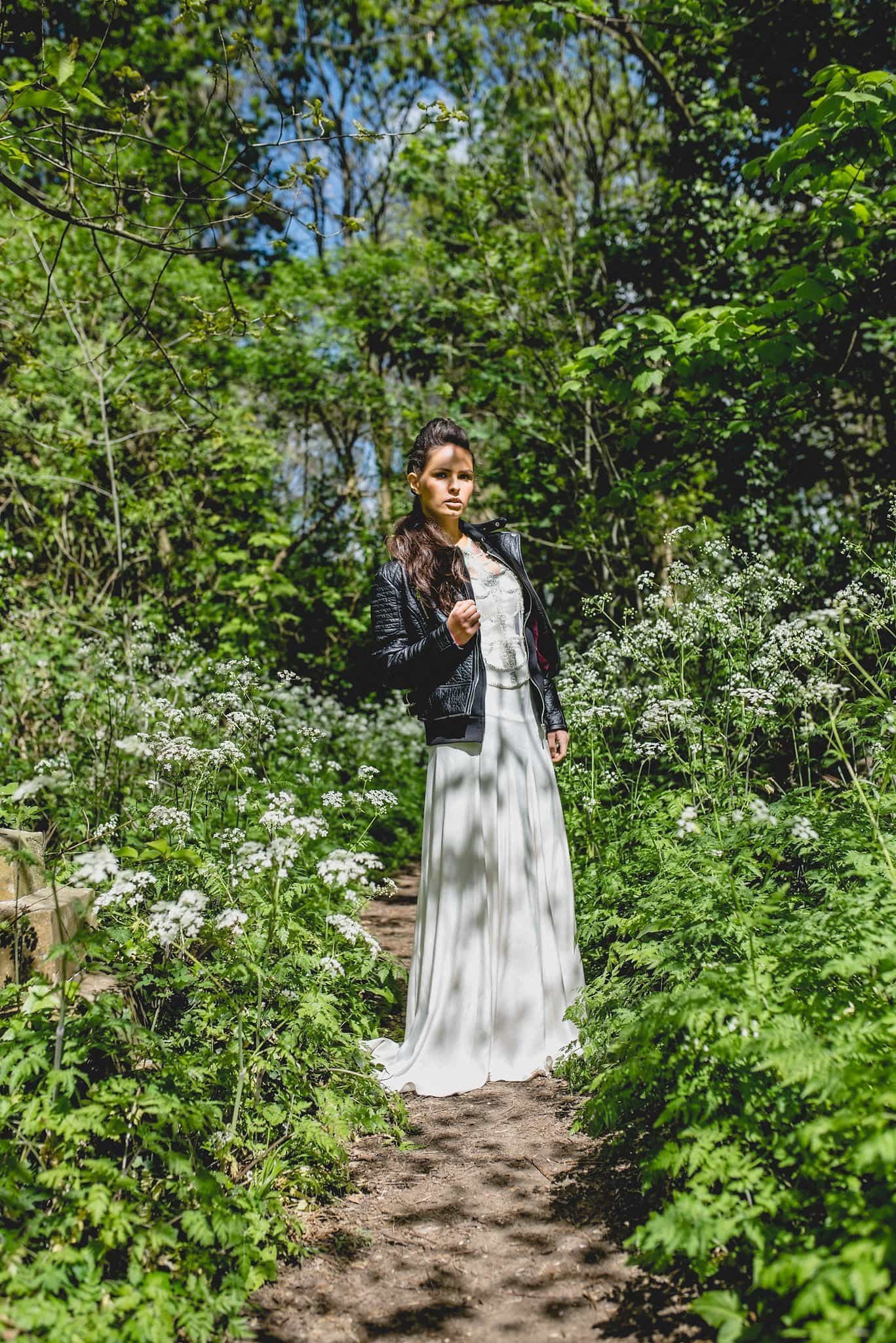 Bride in Catherine Deane separates with leather jacket among wildflowers in Abney Park