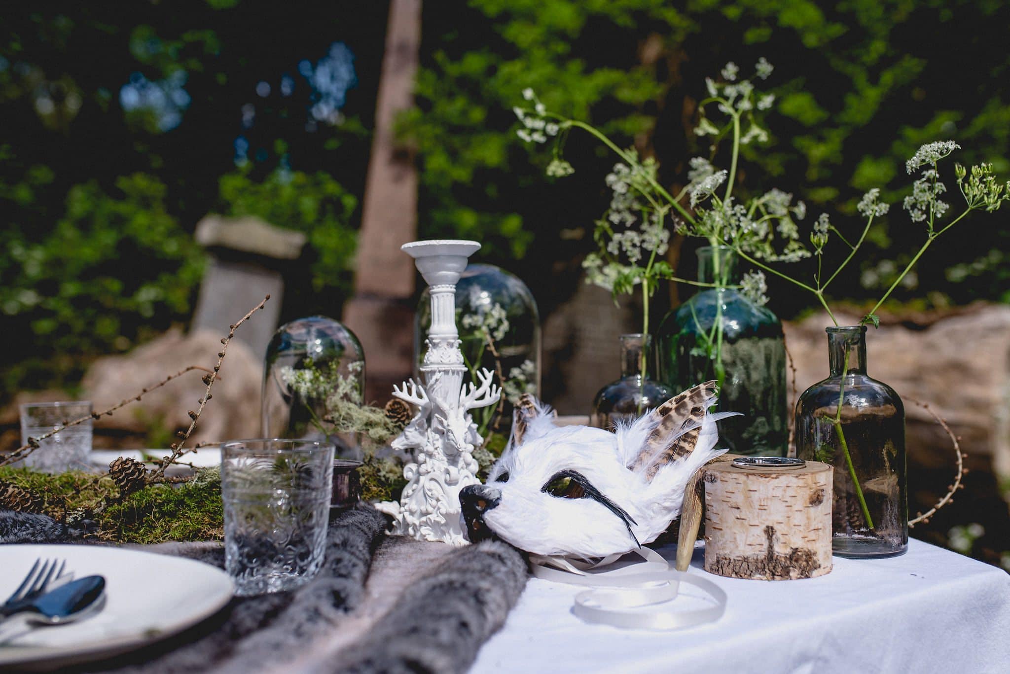 Elements of tablescape including white candlesticks and white feather fox mask