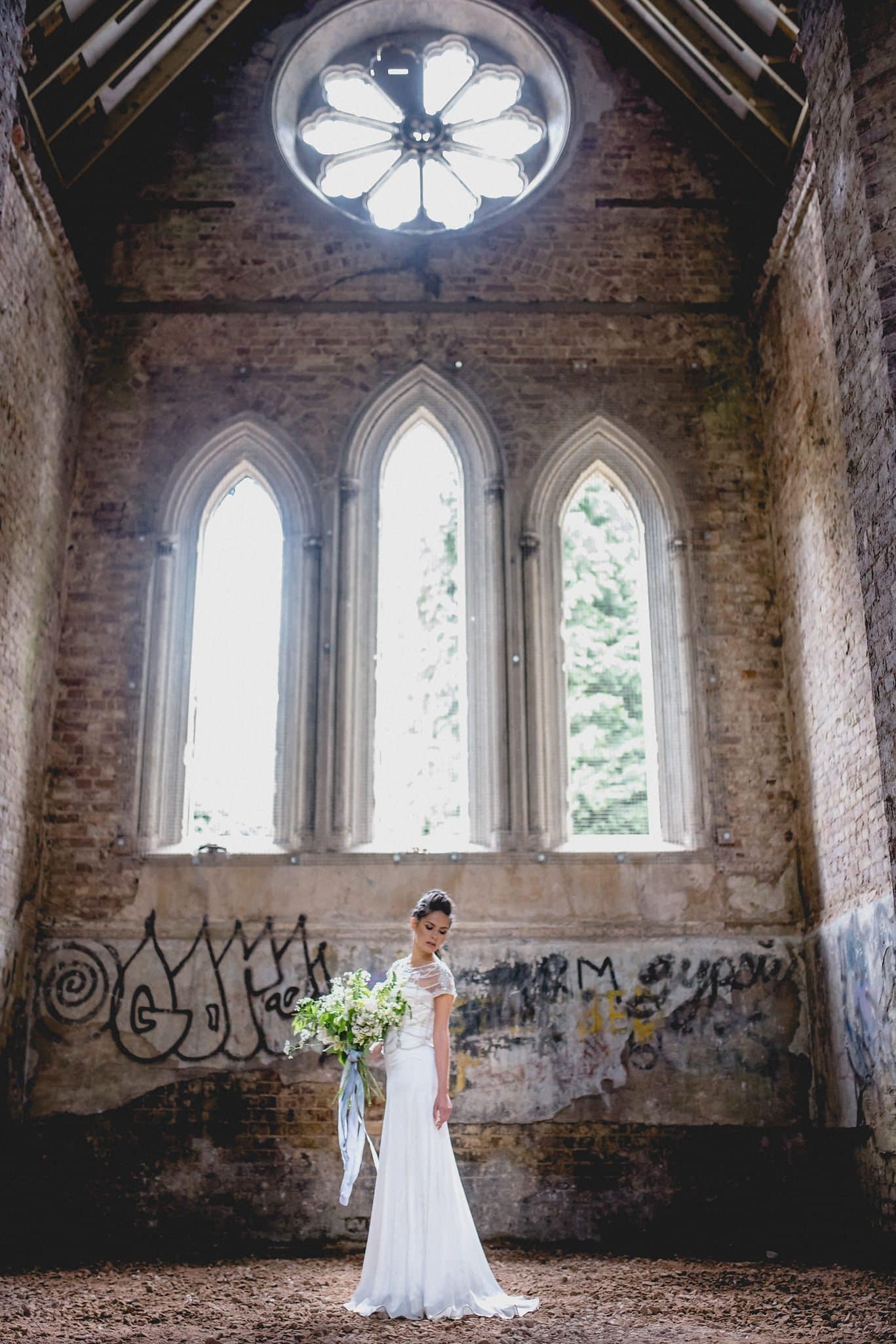 Sunlit bride in the rustic ruined Gothic chapel in Abney Park