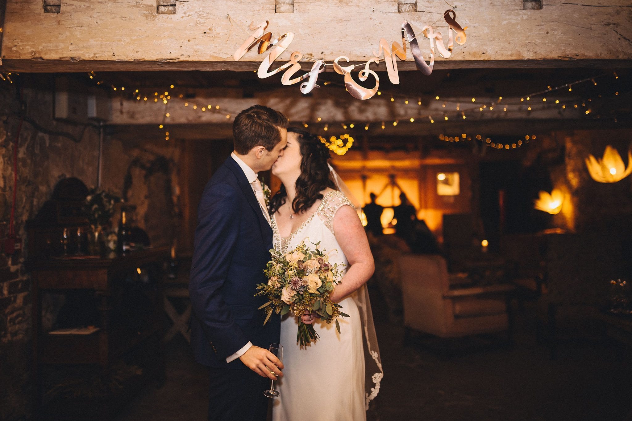 Bride and groom kiss under a Mrs and Mrs sign