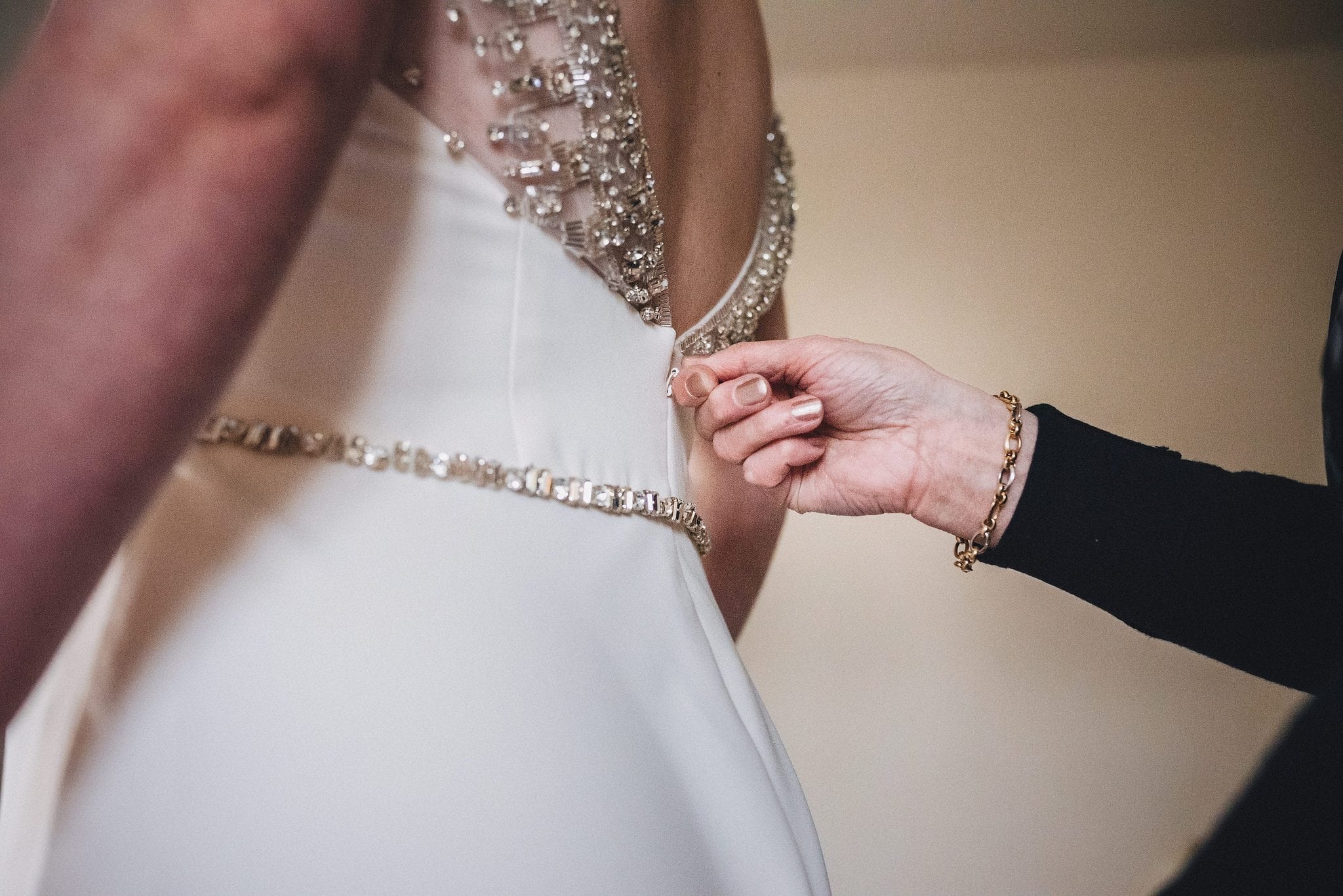 Bride's mother zips her into her wedding dress