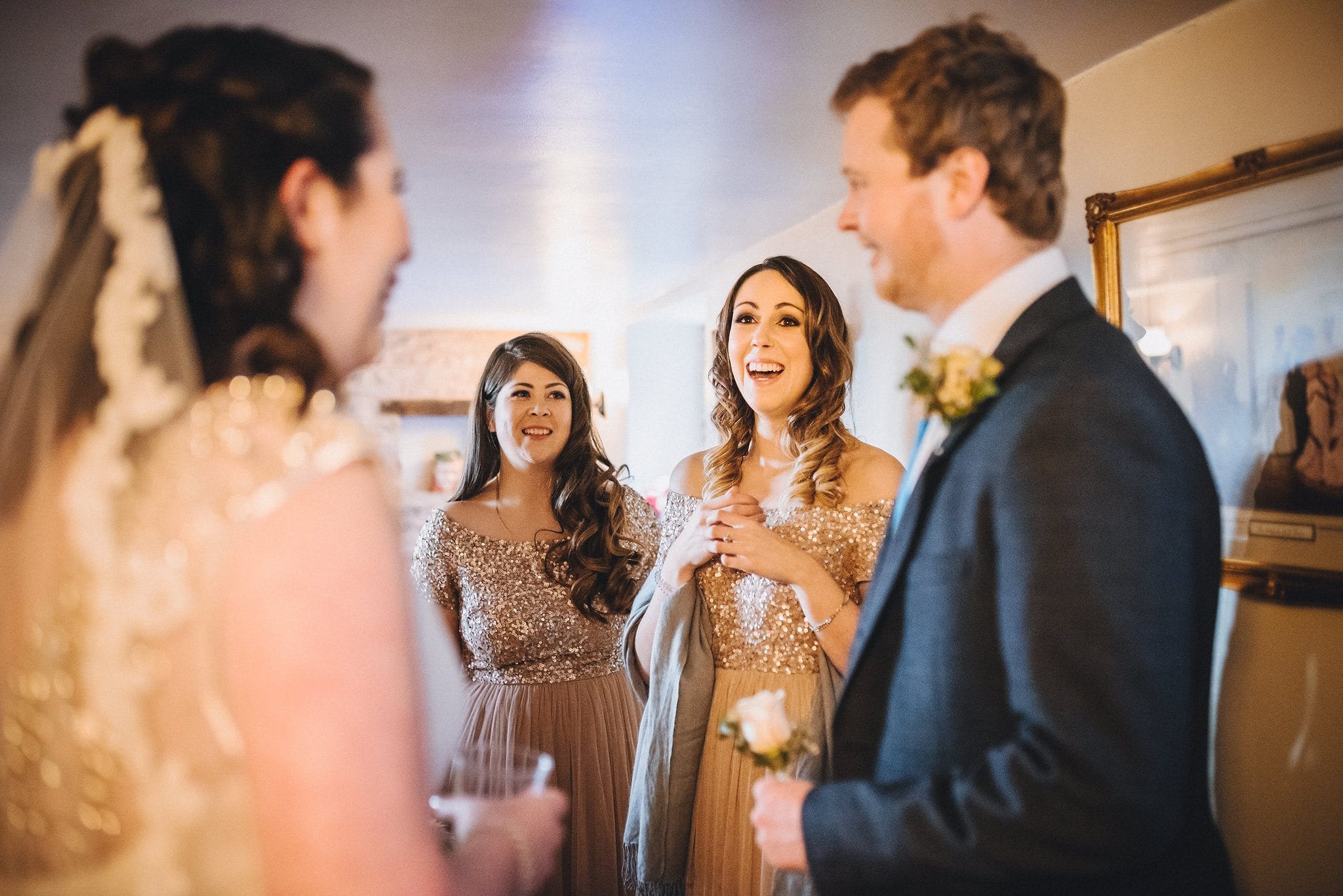 Bridesmaids smile as they see bride in her dress