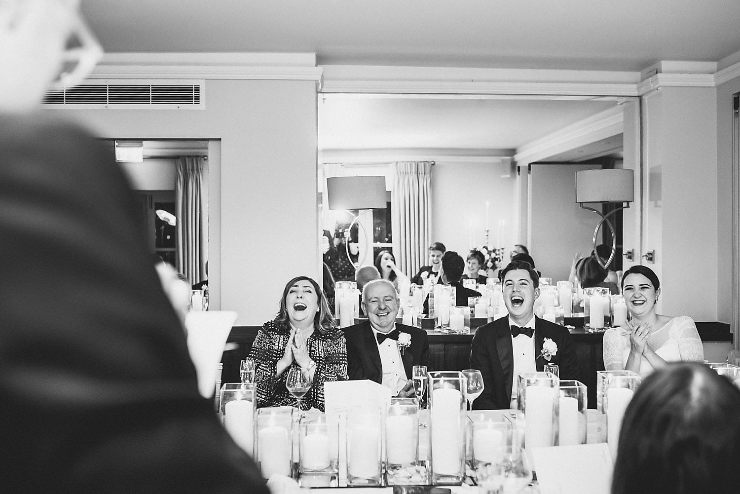 Black and white shot. Everyone laughing during best man's speech