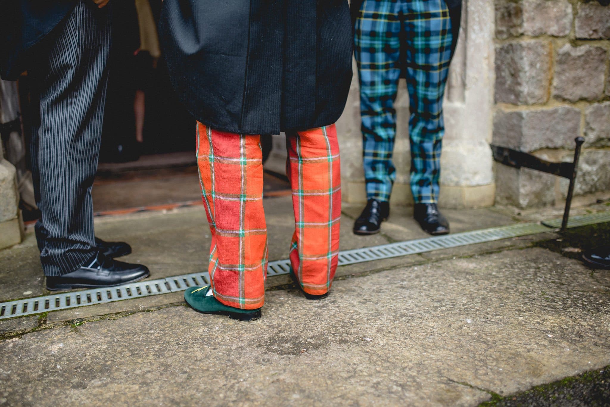 Groom wearing tartan trousers in the church doorway