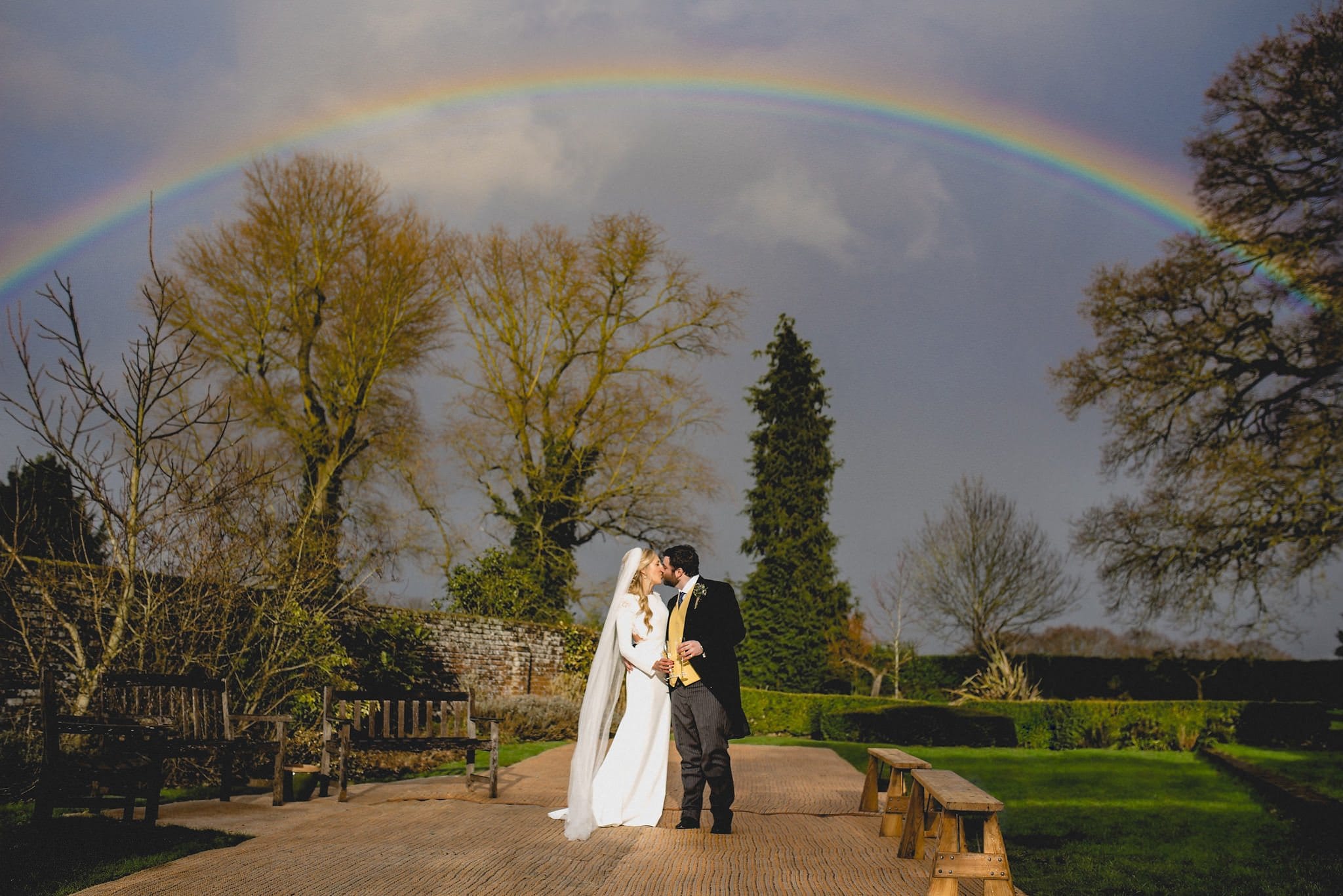 Bride and groom kiss with a rainbow overhead