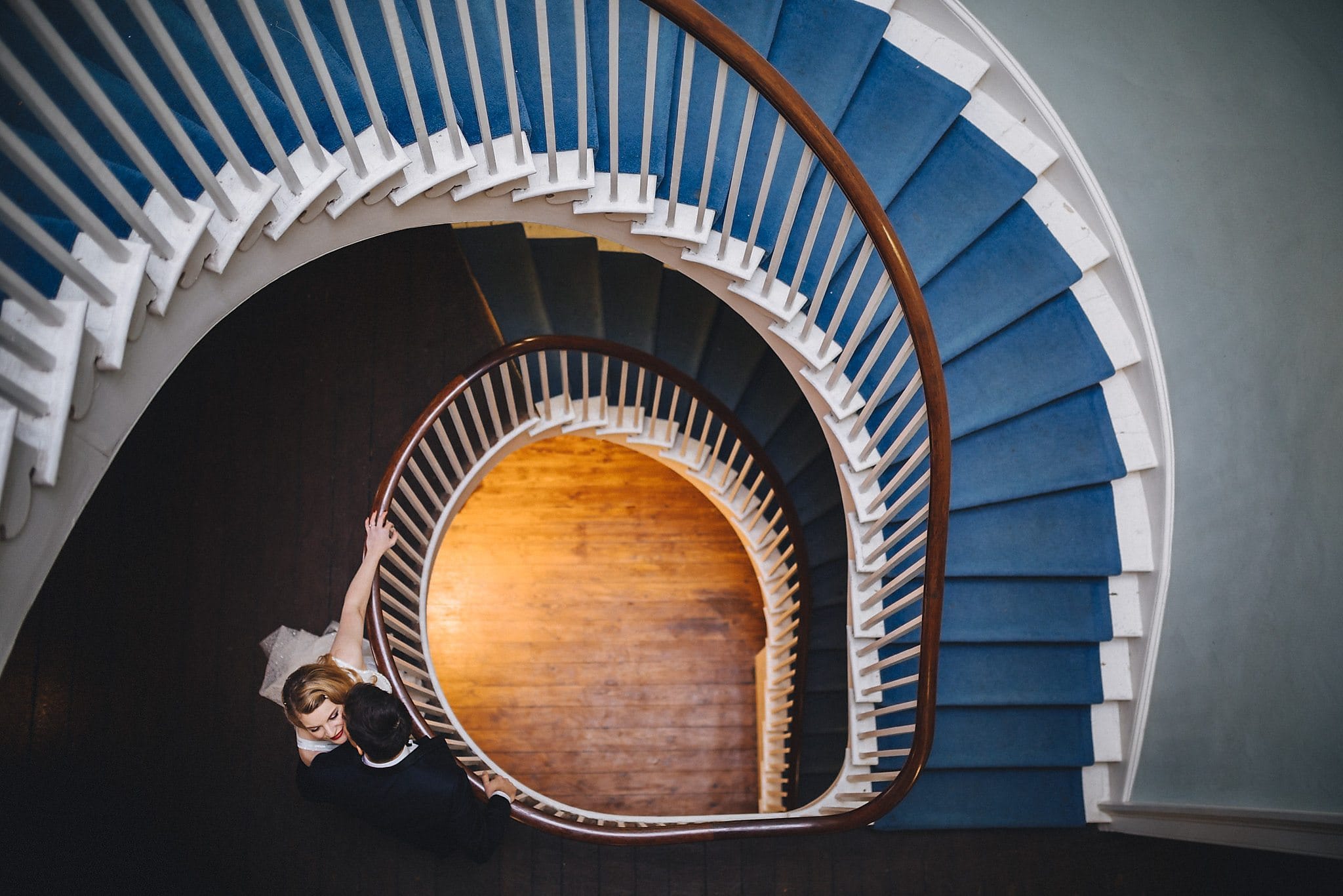 Bride and groom hug on the winding staircase at their Clissold House Wedding