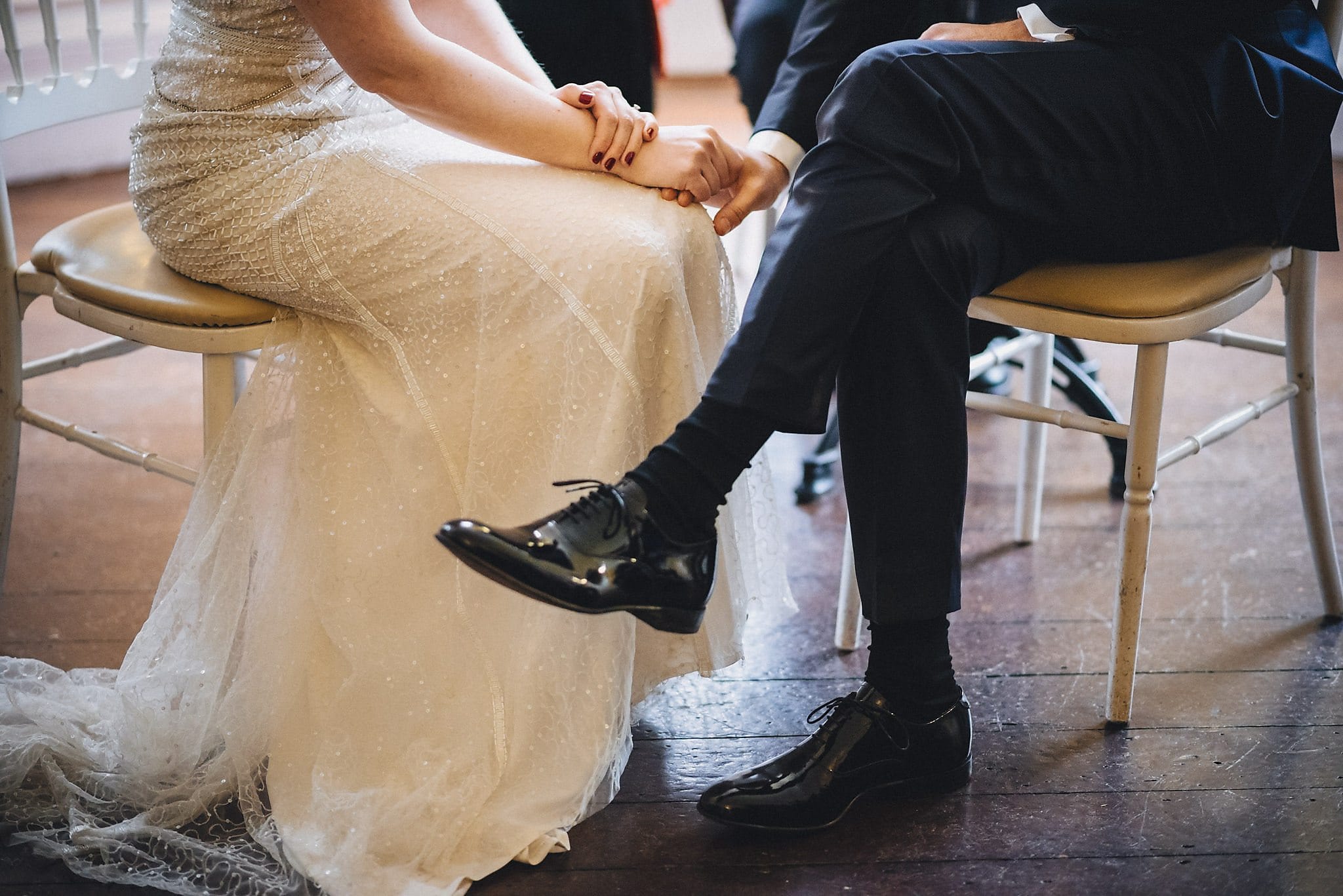 Shot of bride and groom's legs and shoes while seated at wedding ceremony