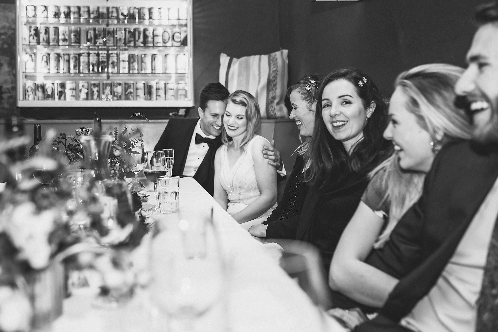 Black and white shot of bride and groom hugging during wedding speeches