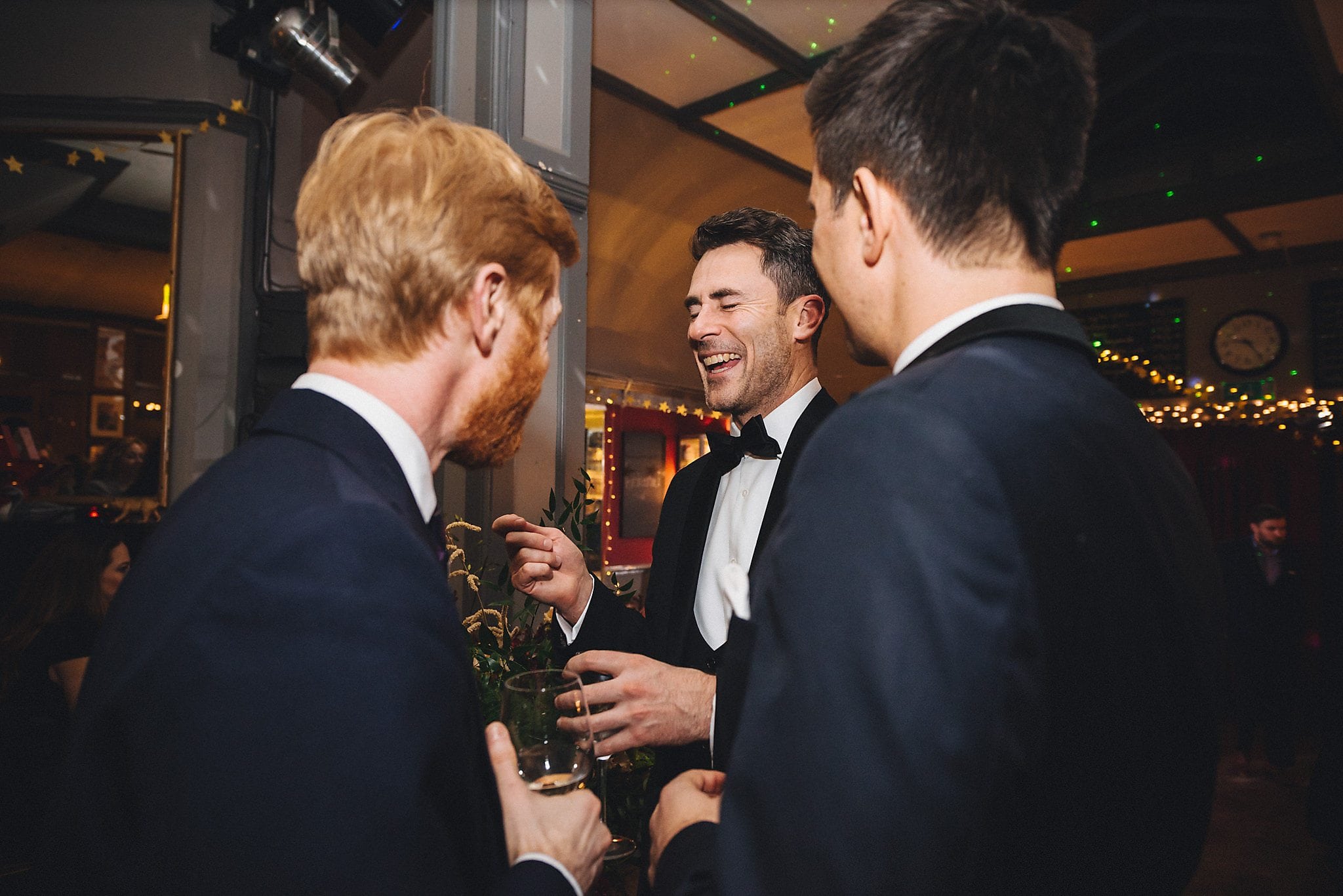 Groom laughing with guests at reception