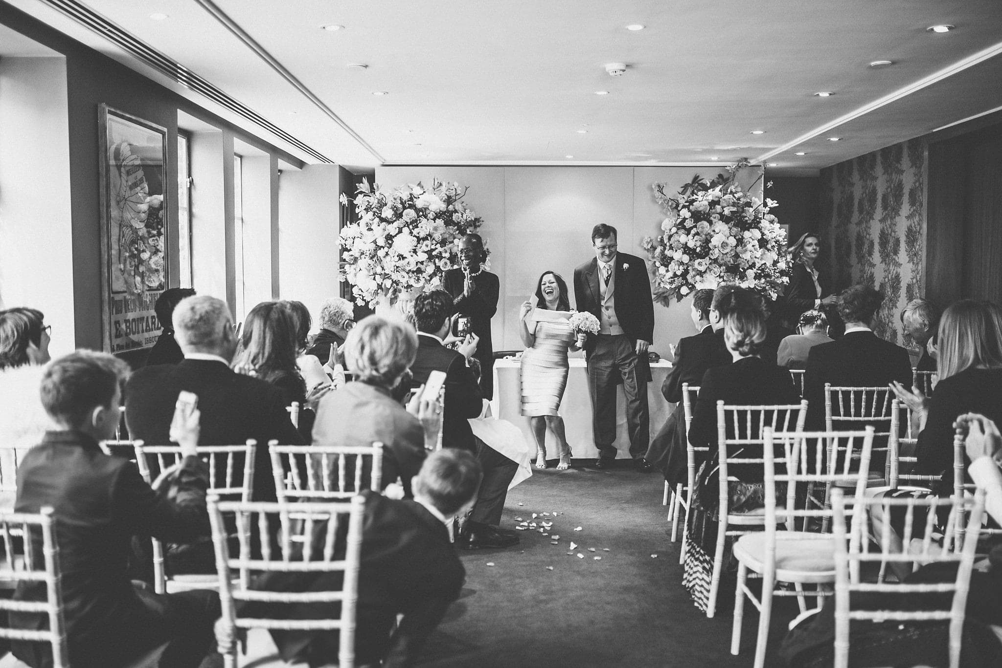 Black and white shot of couple laughing together at the end of their wedding ceremony