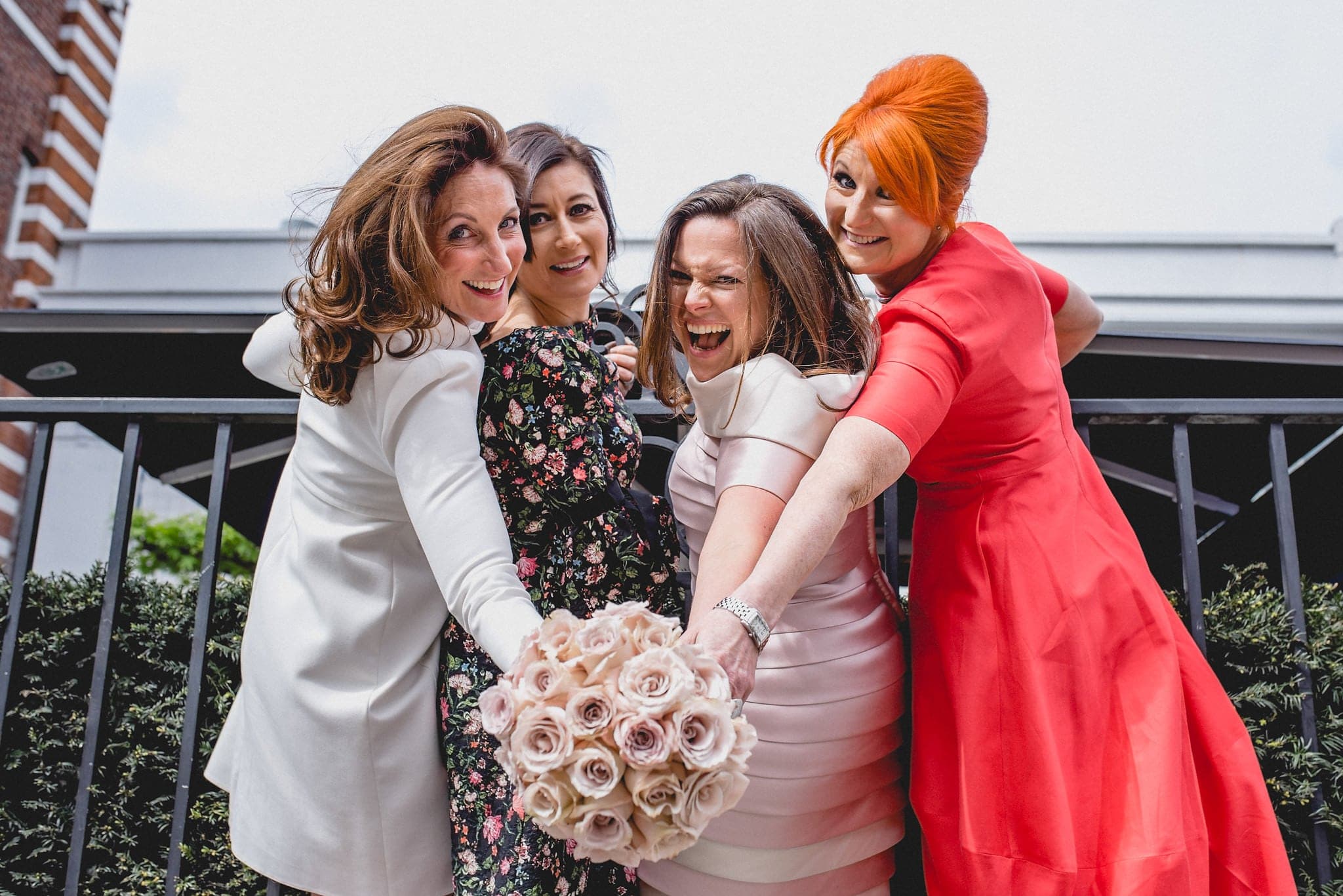 Bride and friends pose on railings of Chelsea venue