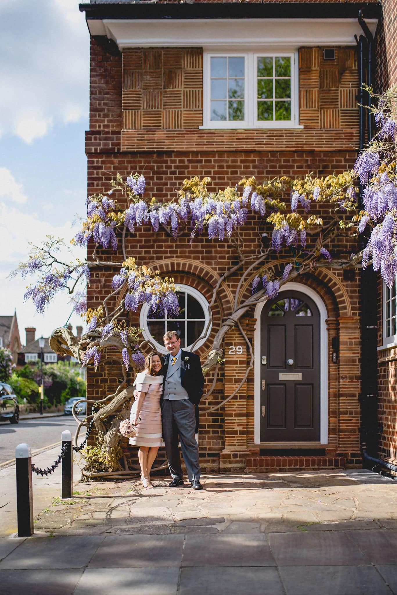 Bride and groom pose outside building draped in wisteria