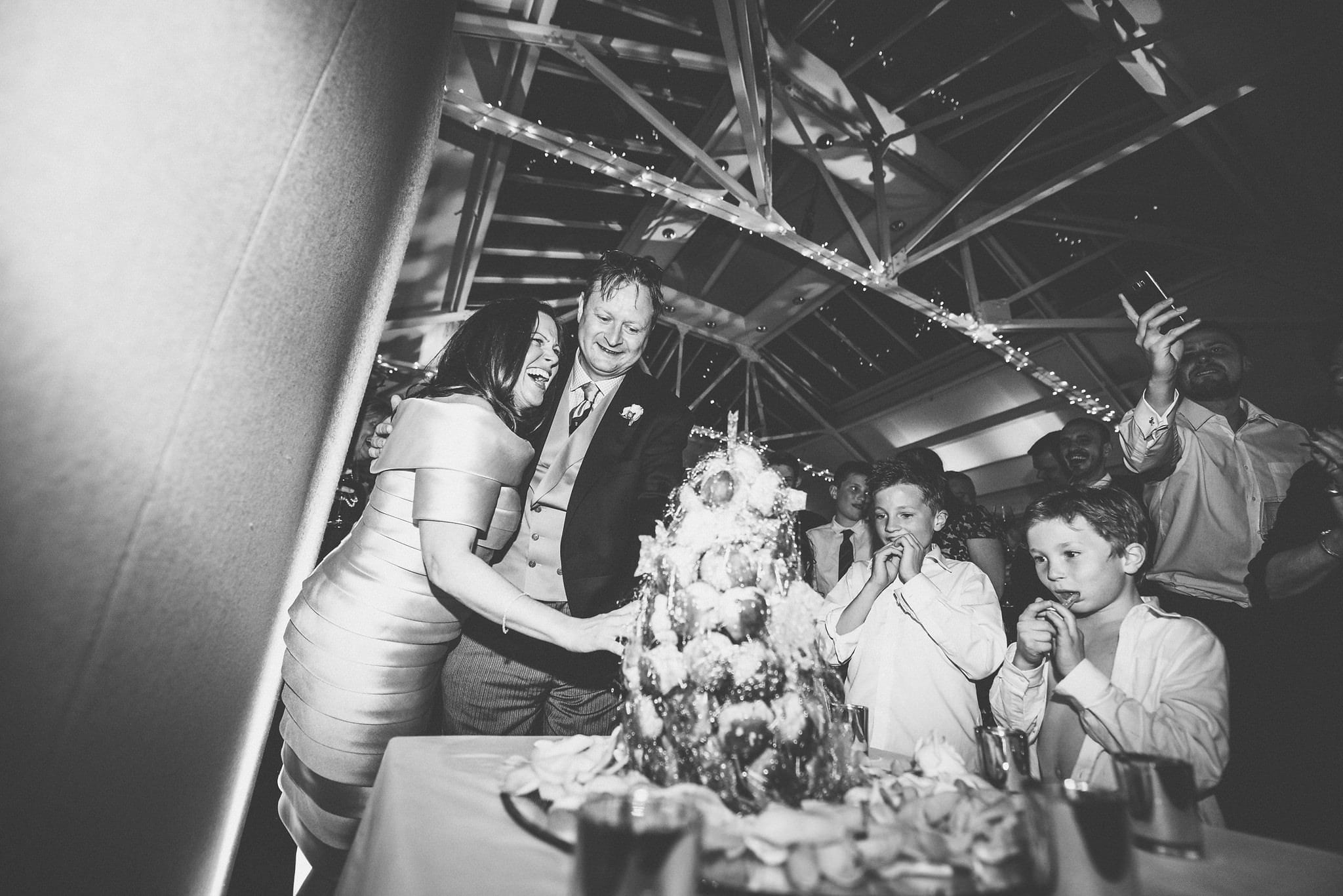 Black and white shot of bride and groom cutting into croque en bouche