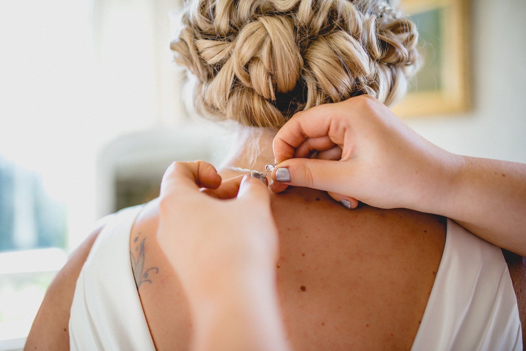 Bride has necklace fastened as she gets ready for her Shendish Manor wedding