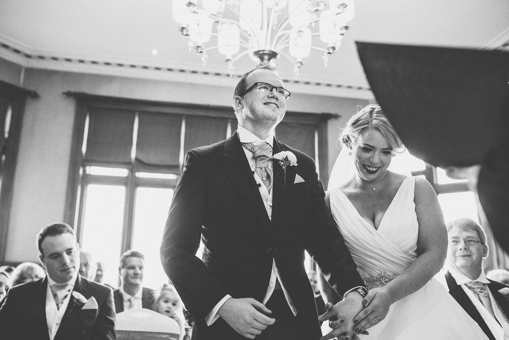 Black and white shot of bride and groom laughing together during their wedding ceremony