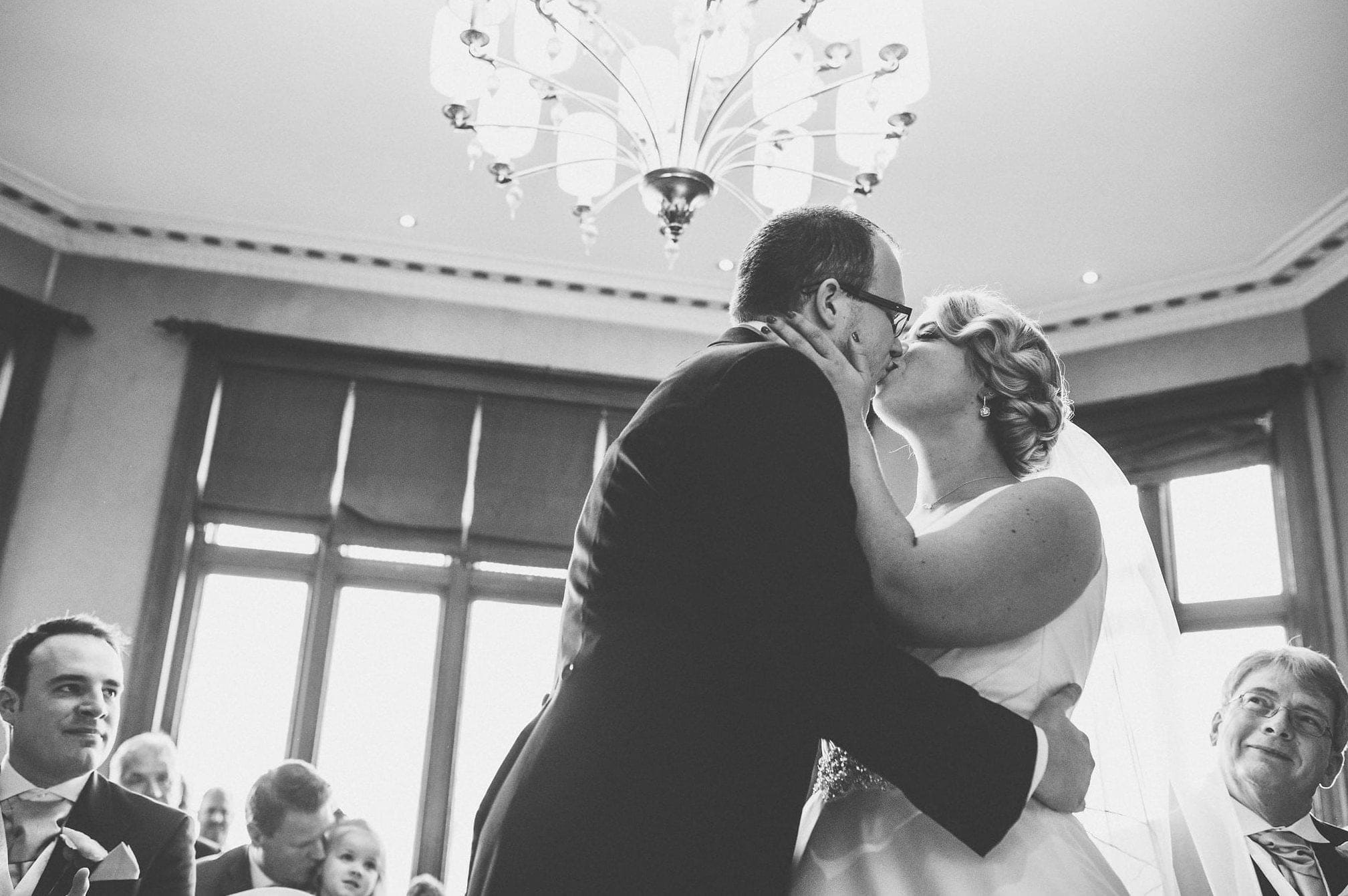 Black and white shot of bride and groom kissing during wedding ceremony