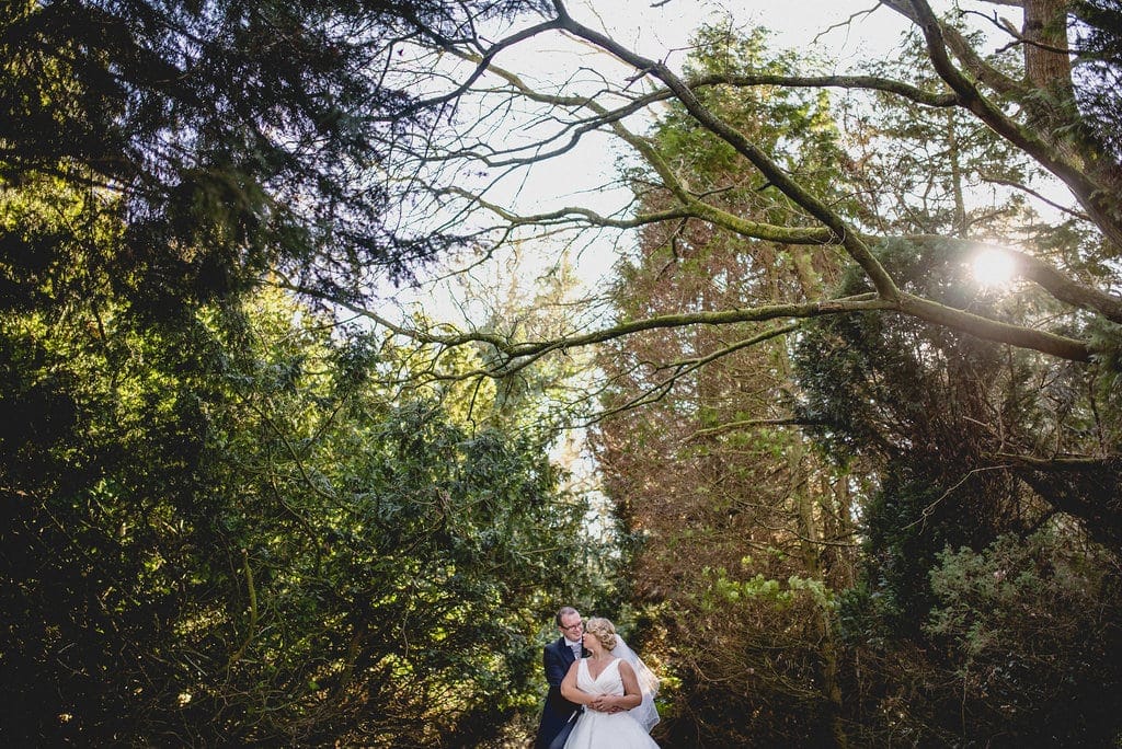 Bride and groom embrace in the woodland in the grounds of Shendish Manor