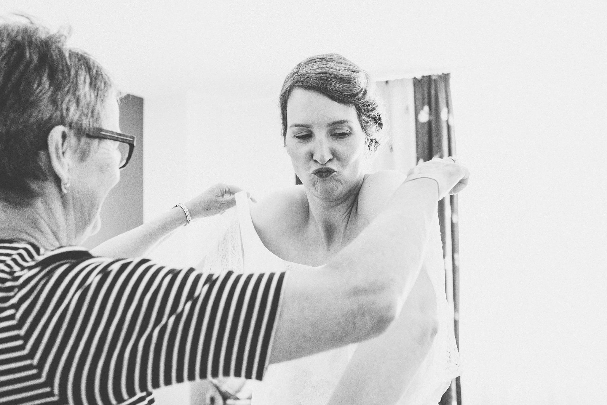 Bride's mum helping her put on her wedding dress