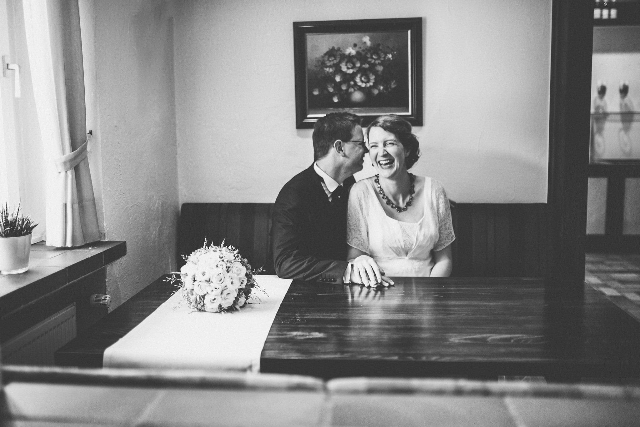 Groom whispering in the bride's ear in a booth at their Heartfelt Destination Wedding in Germany | Maria Assia Photography