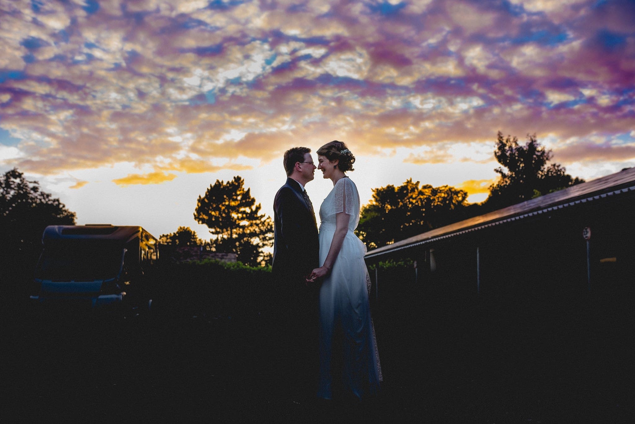 Bride and Groom standing in in front of a sunset sky at their Heartfelt Destination Wedding in Germany | Maria Assia Photography