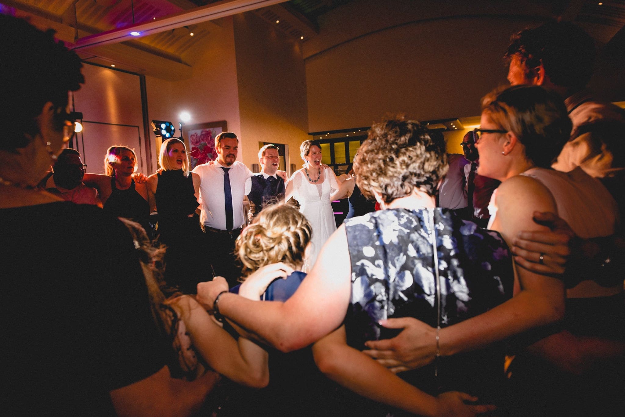 Bride, Groom and their wedding guests dancing the conga