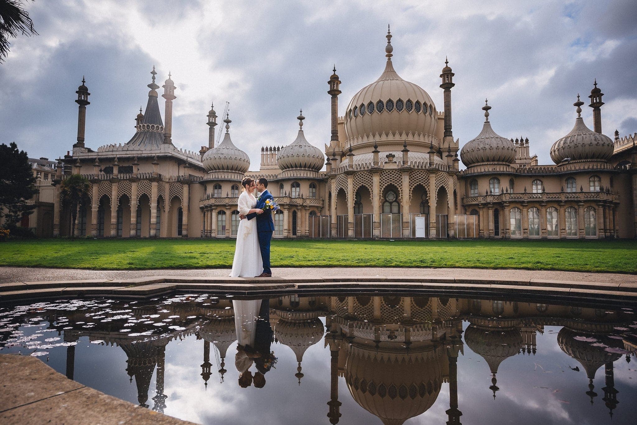 Bride and groom hugging in front of the Brighton Royal Pavilion with a reflection in the pond