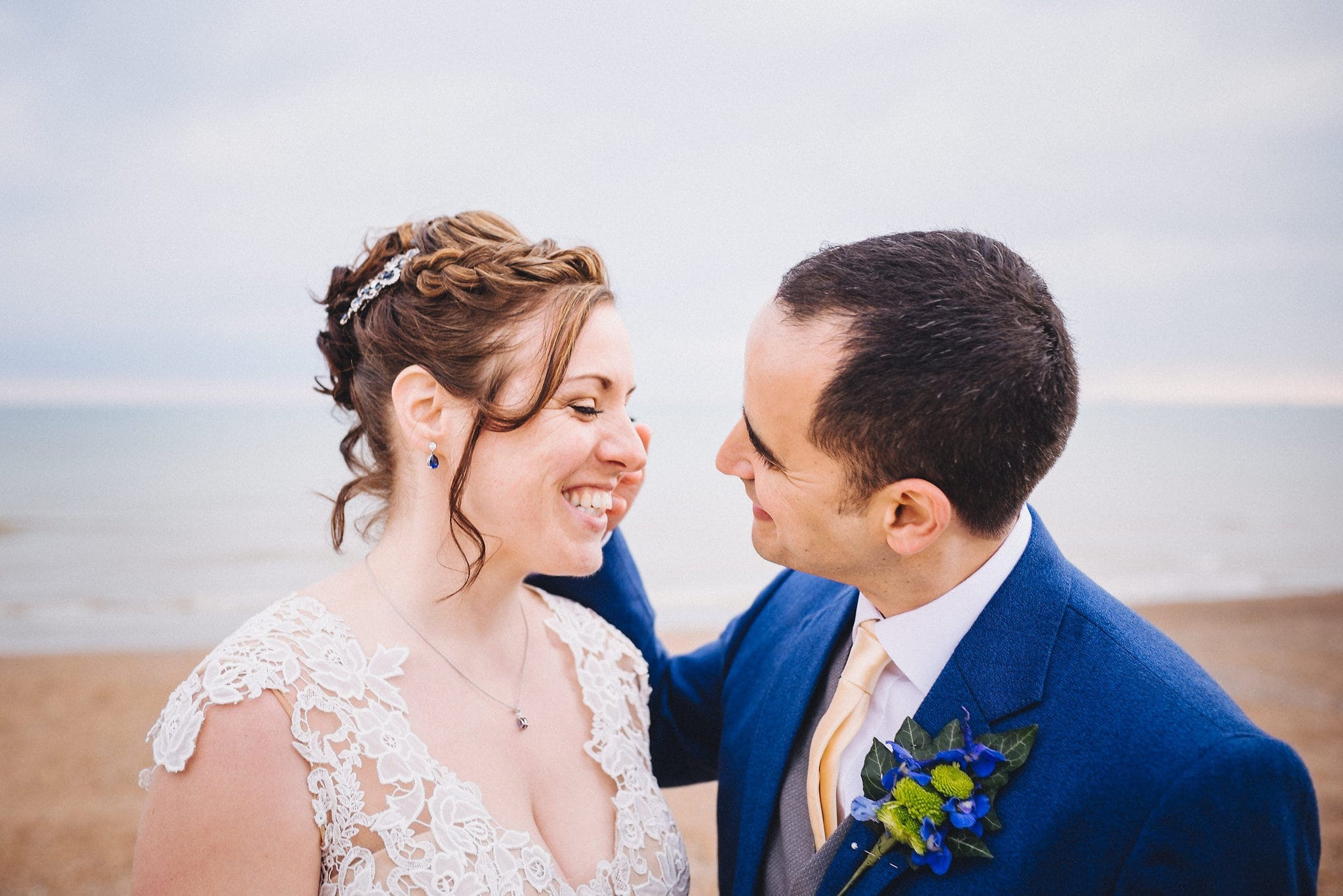 Bride and groom laugh together on Brighton beach