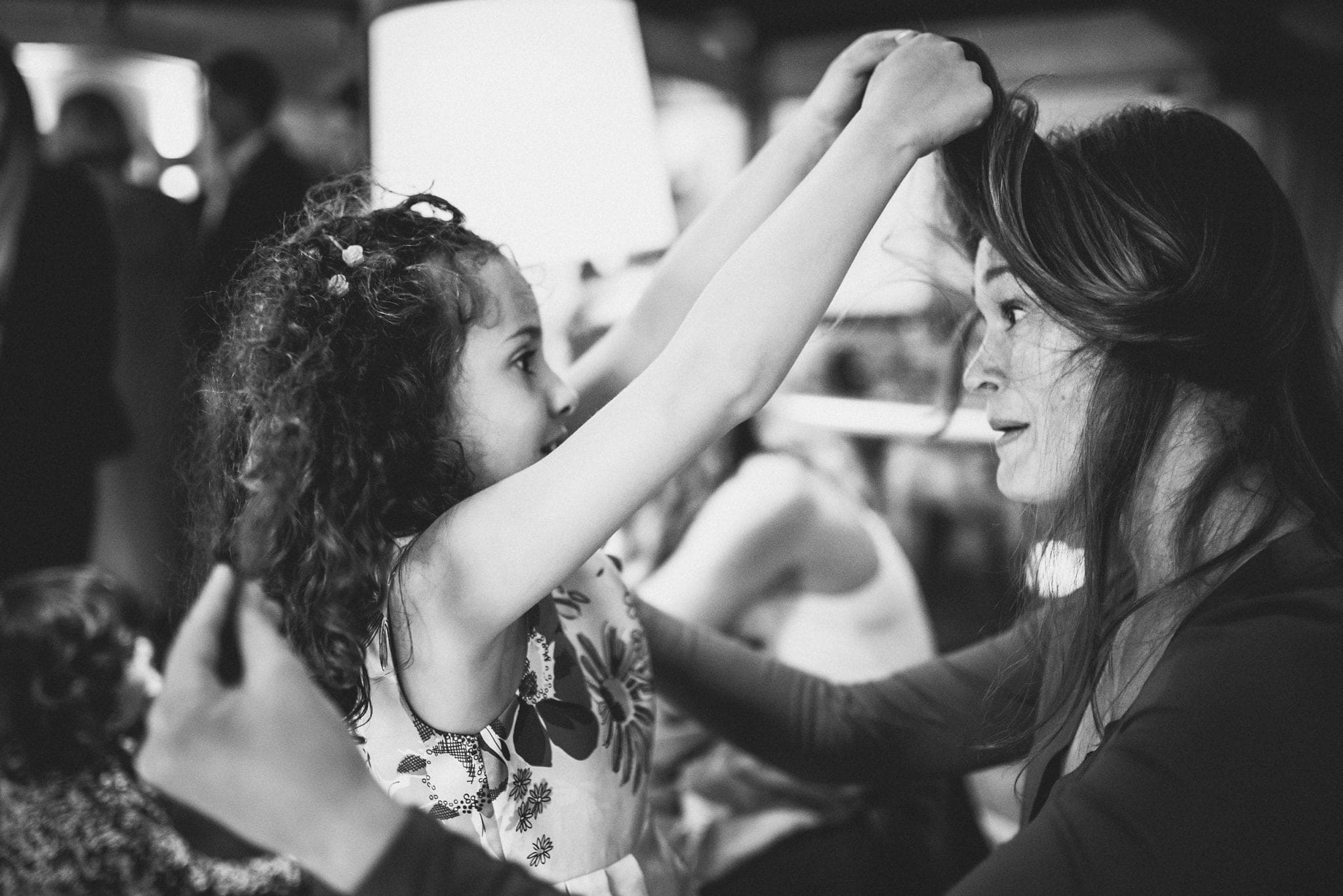 Child plays with guest's hair at wedding reception