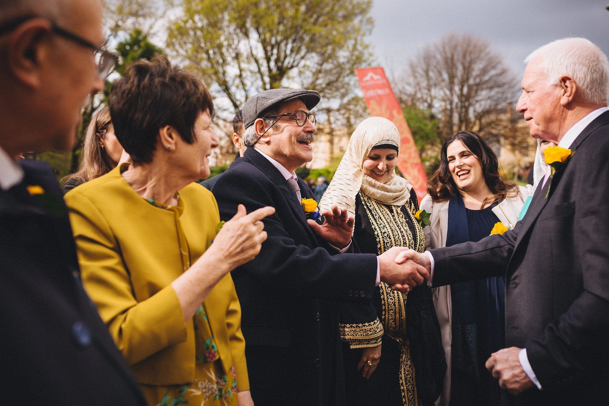 Father of the bride greets father of the groom with a handshake