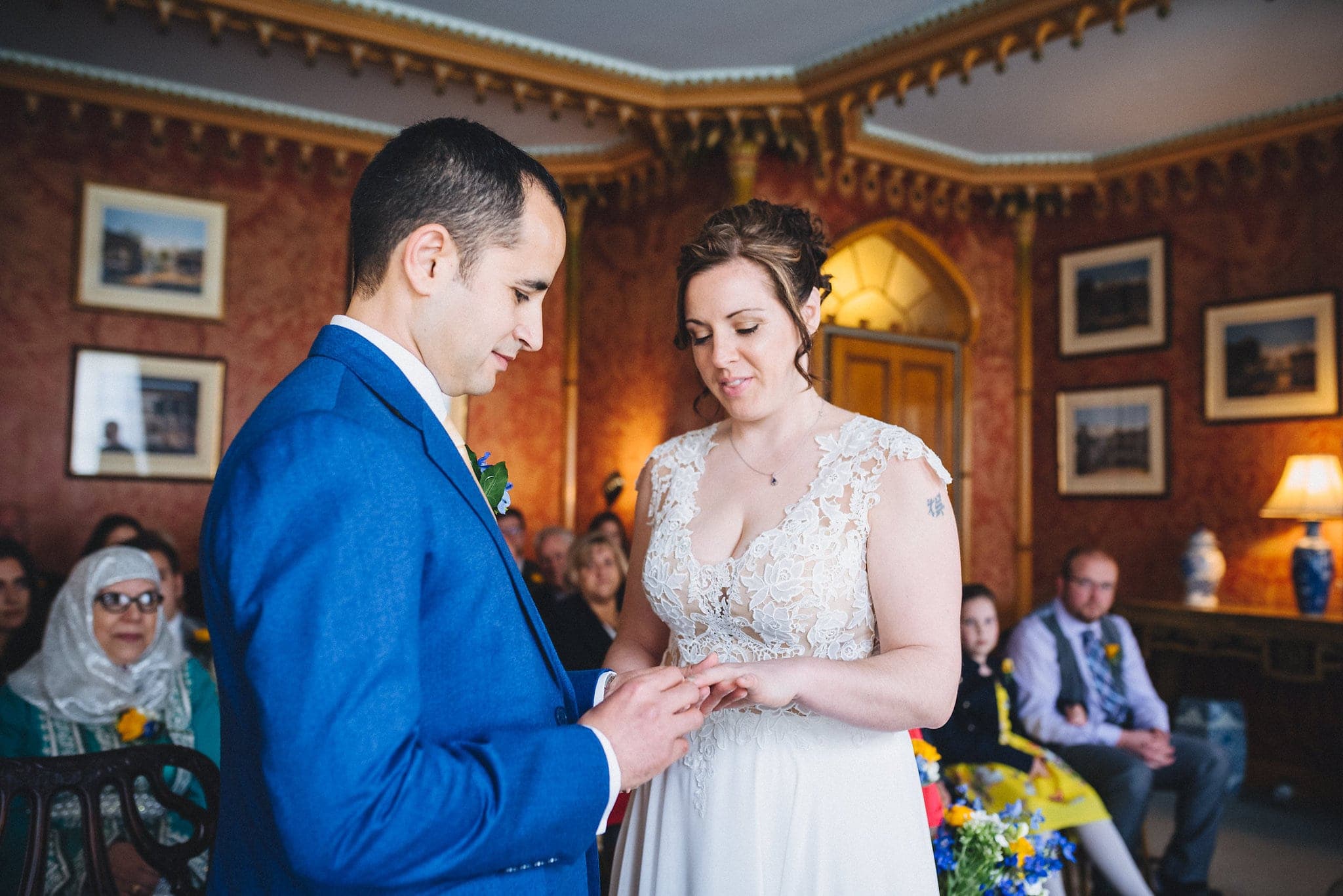 Groom places bride's ring on her finger at Brighton Royal Pavilion wedding