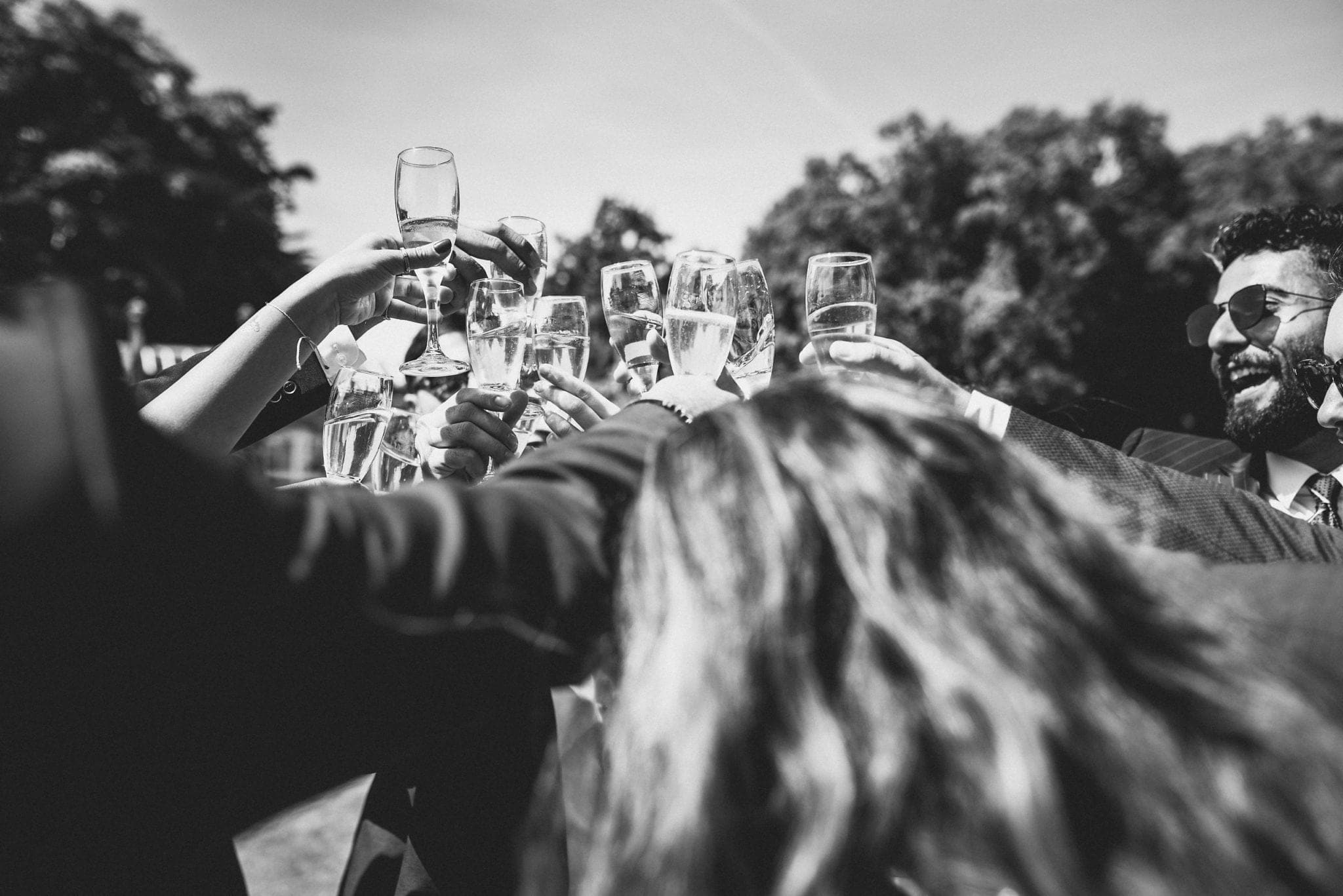 Black and white shot of large toast with many champagne glasses clinking together