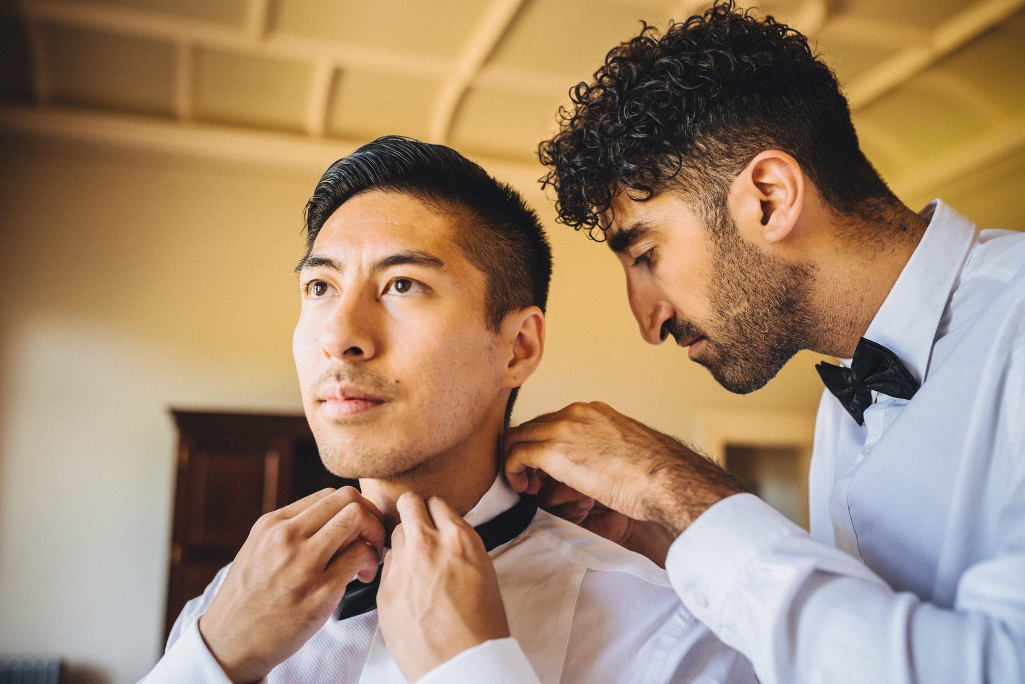 Groomsman fastens groom's bowtie