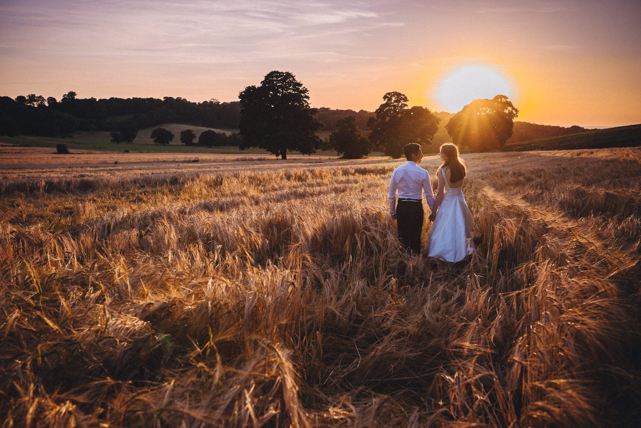 Bride and groom in wheatfield at sunset