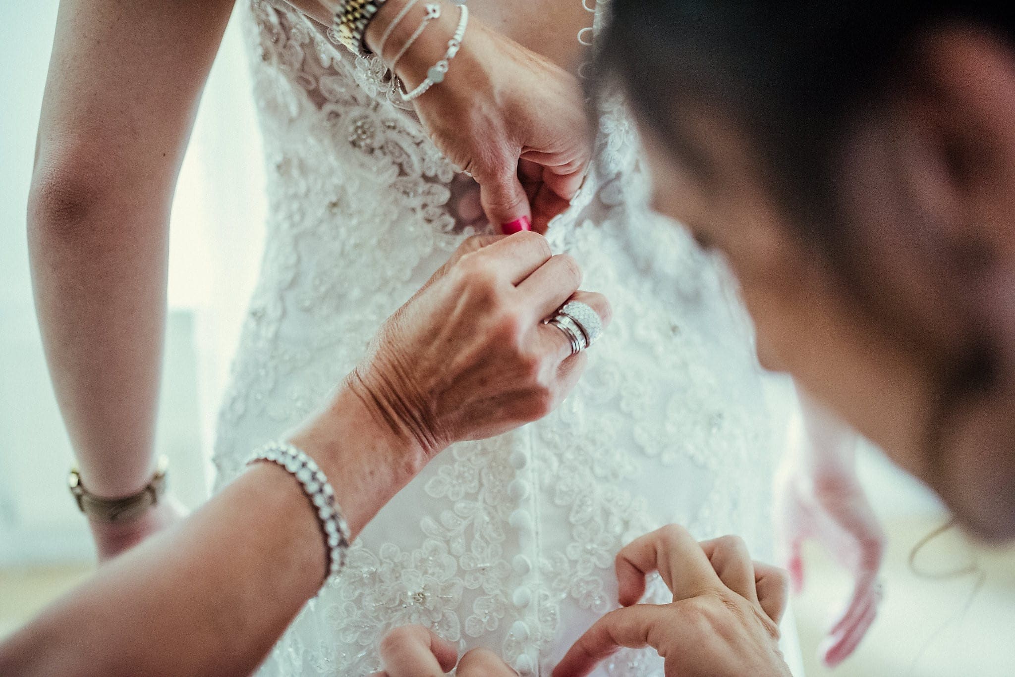 Buttons being done on the back of the bride's dress