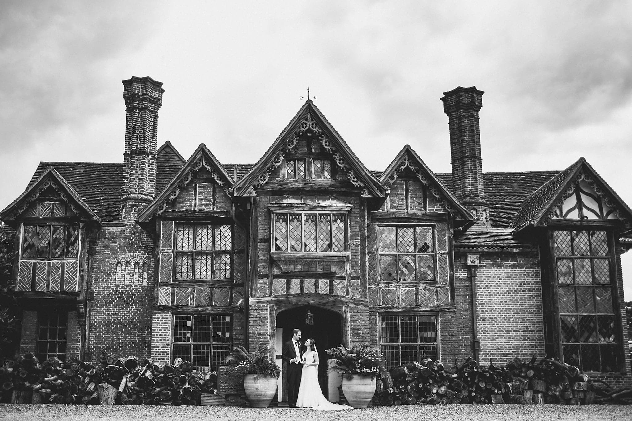 Black and white shot of bride and groom in front of Tudor Manor at Dorney Court